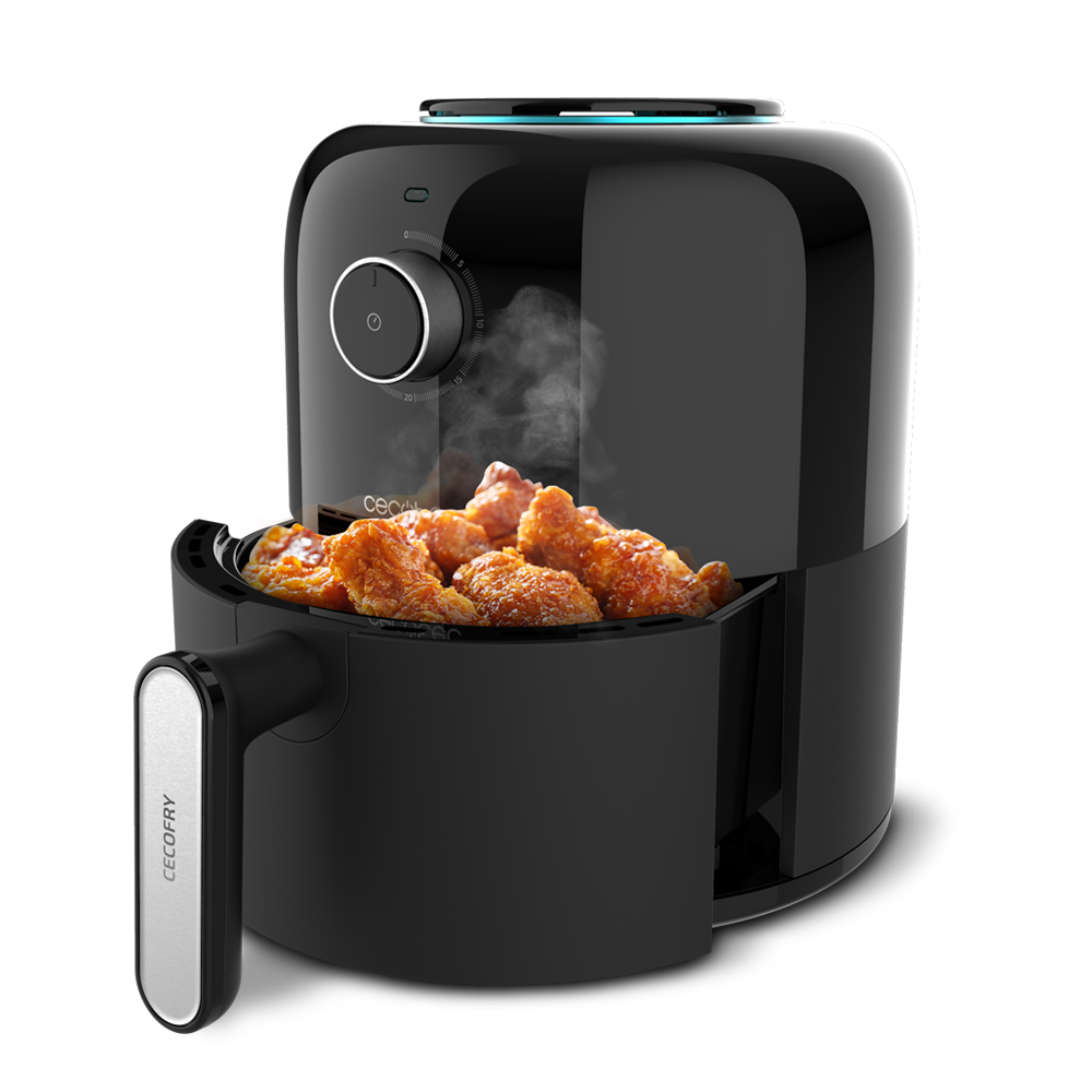 Freidora de aire negra con alitas de pollo. Tiene un asa, un temporizador y vapor saliendo.