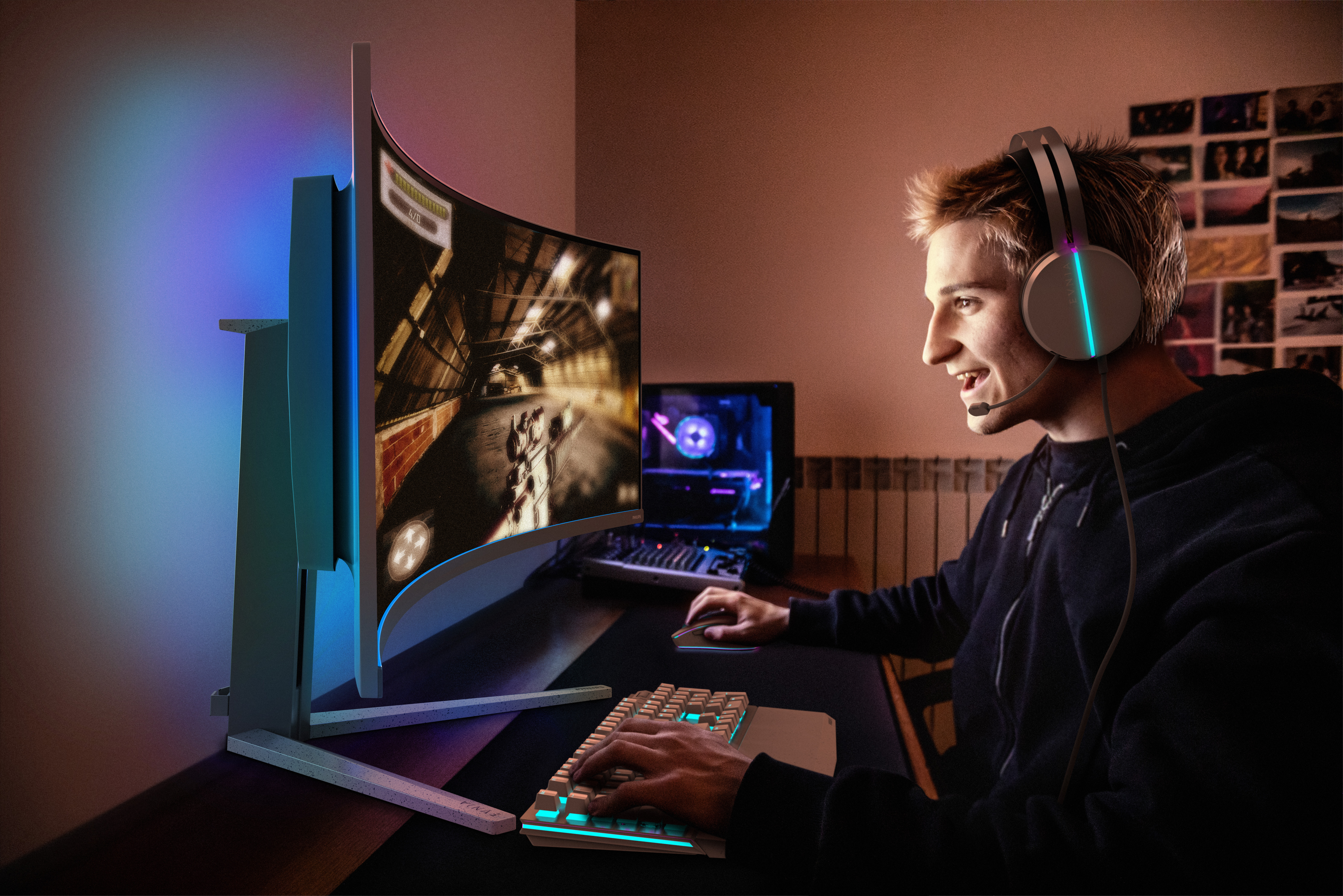 Ein junger Mann mit Kopfhörern spielt an einem gekrümmten Monitor. Tastatur und Maus sind sichtbar. Die Szene ist drinnen.
