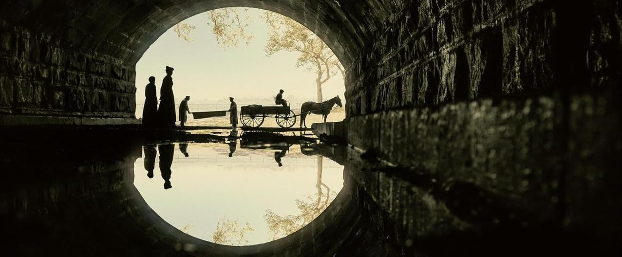 Silhouetten unter einem Torbogen. Eine Pferdekutsche und Figuren. Spiegelungen im Wasser. Dunkle, stimmungsvolle Szene.