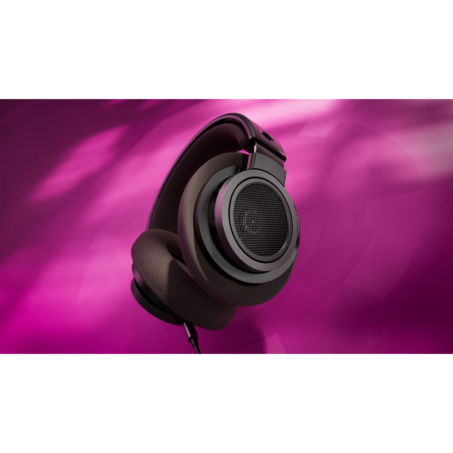 Cuffie nere con padiglioni grigi su sfondo rosa. Un cavo pende. Le cuffie sono l'elemento principale.