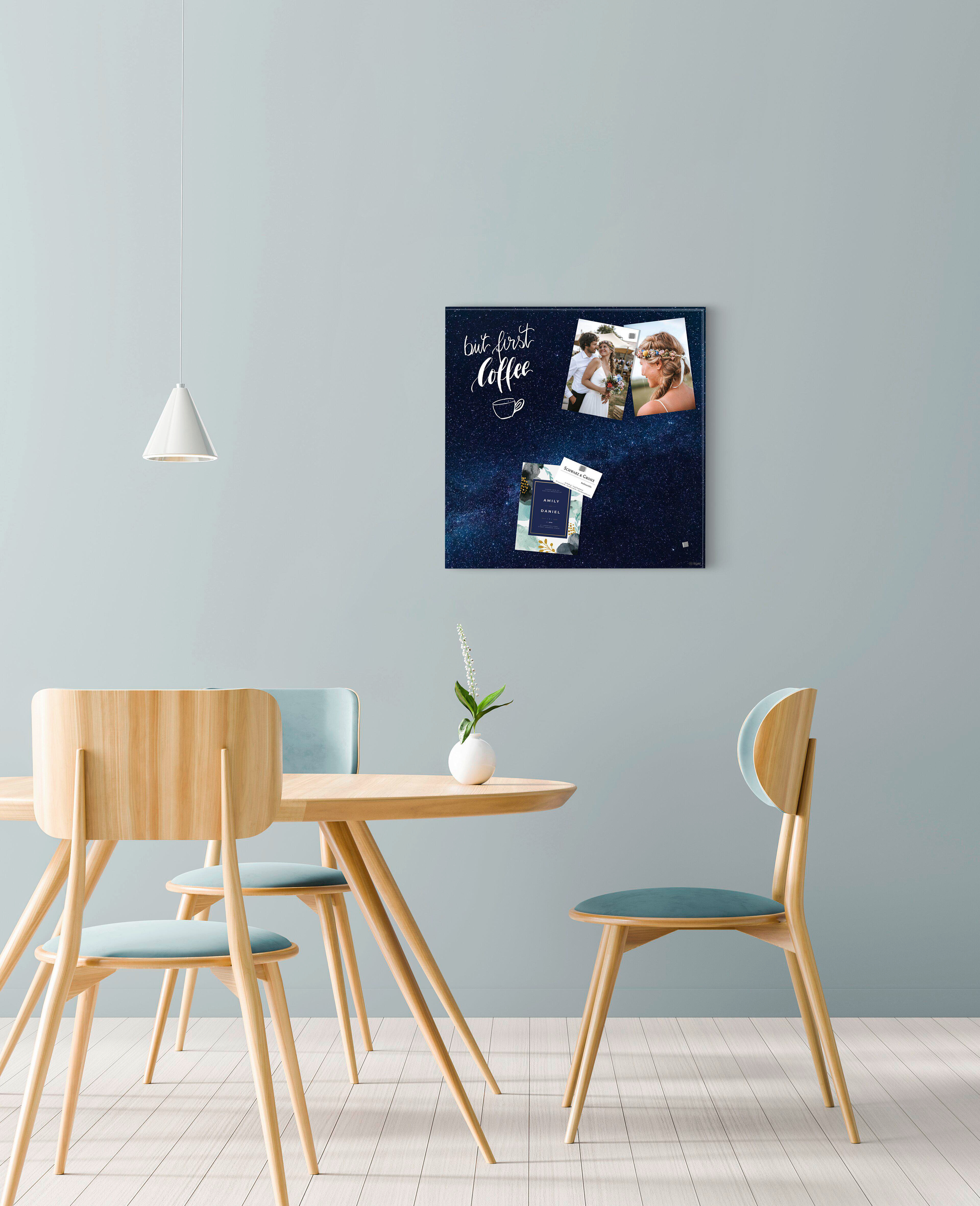 Esszimmer mit Holzmöbeln. Eine Tafel mit der Aufschrift 'but first coffee' hängt mit Fotos. Über dem Tisch hängt eine Lampe.