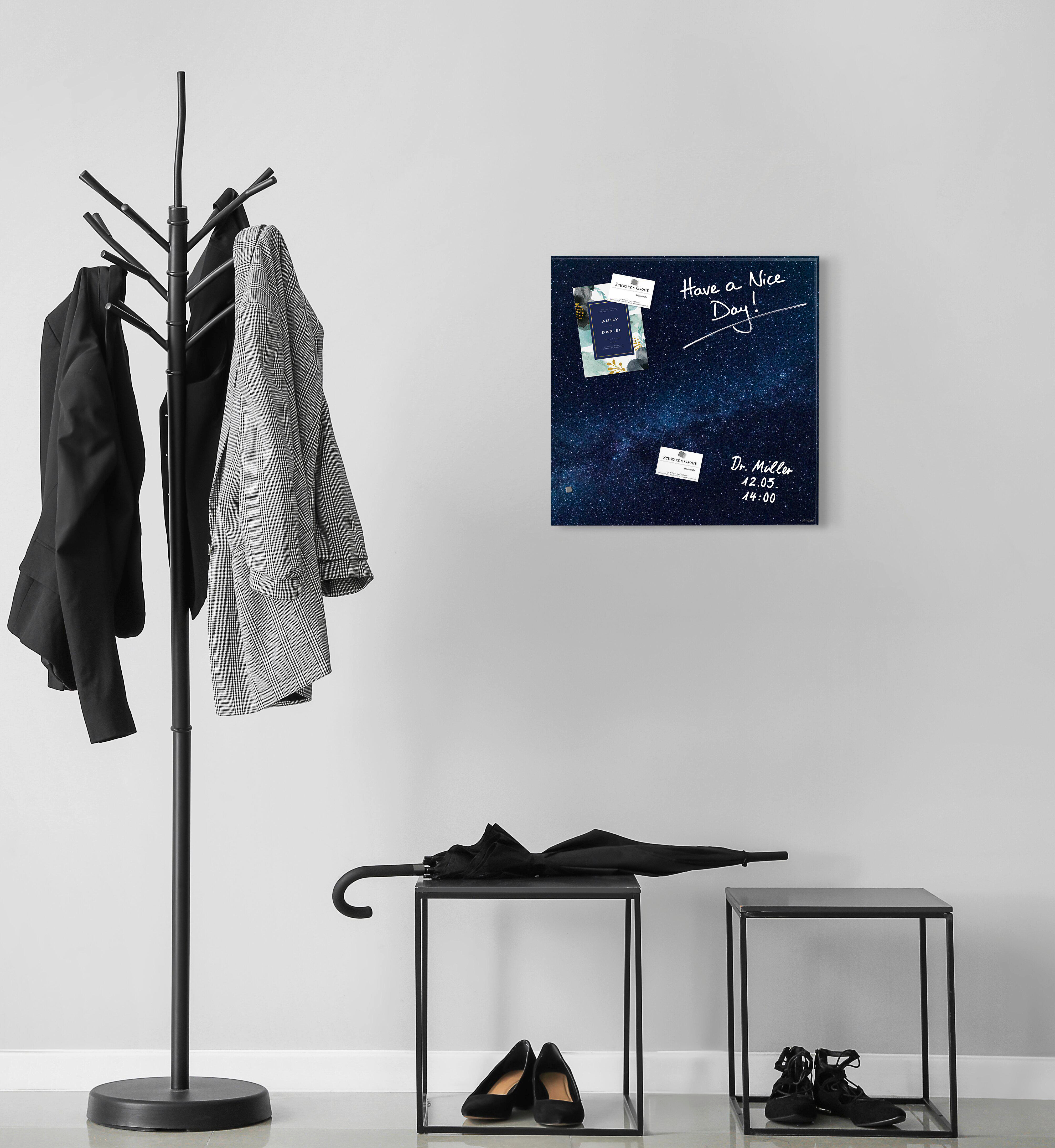 Eine Garderobe mit Jacken, ein Tisch mit Schuhen und Schirm und eine Tafel mit Notizen, alles in einem Raum.