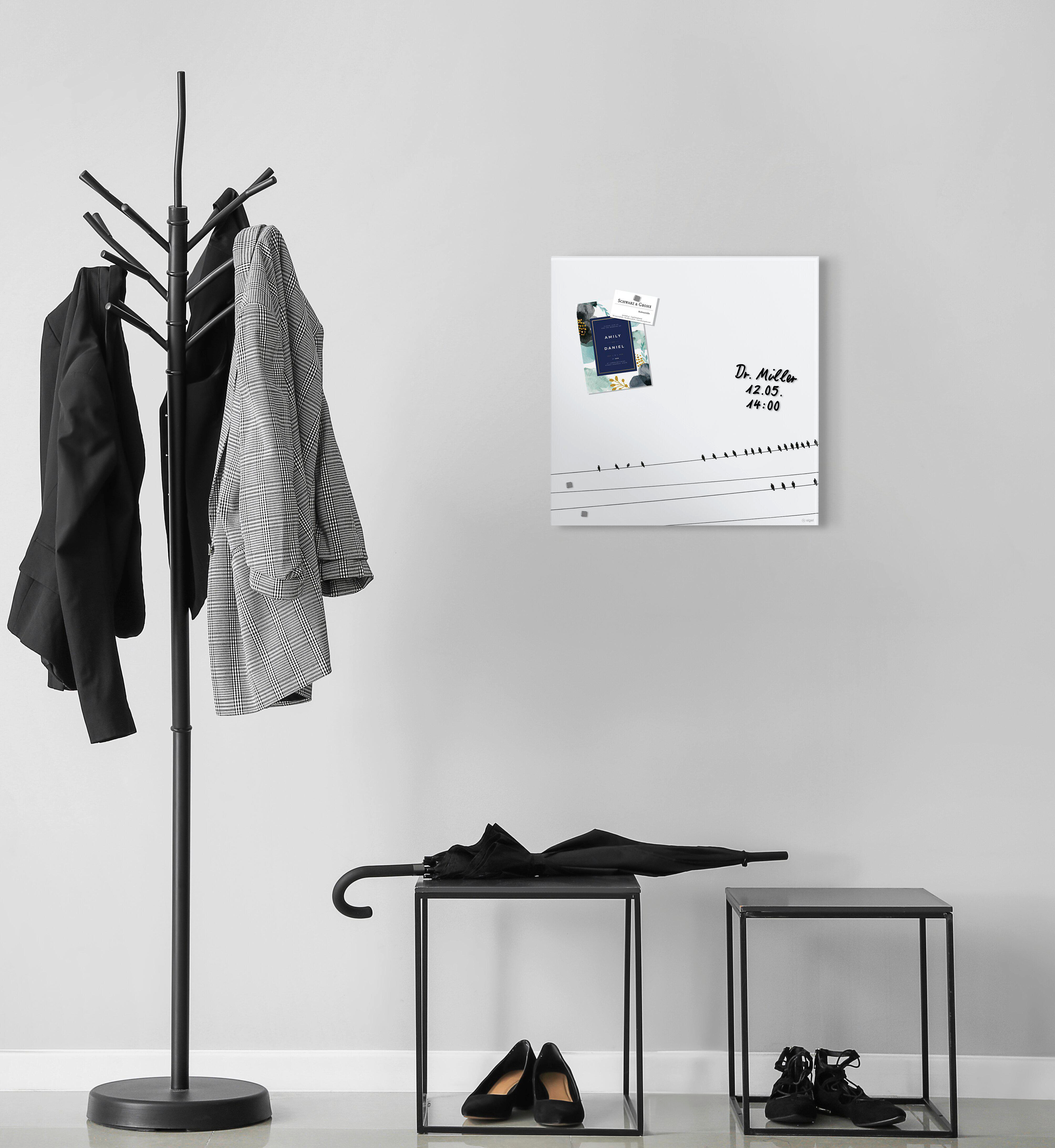 Eine Garderobe mit Jacken, eine Tafel mit Notizen und zwei kleine Tische mit Schuhen und einem Regenschirm.