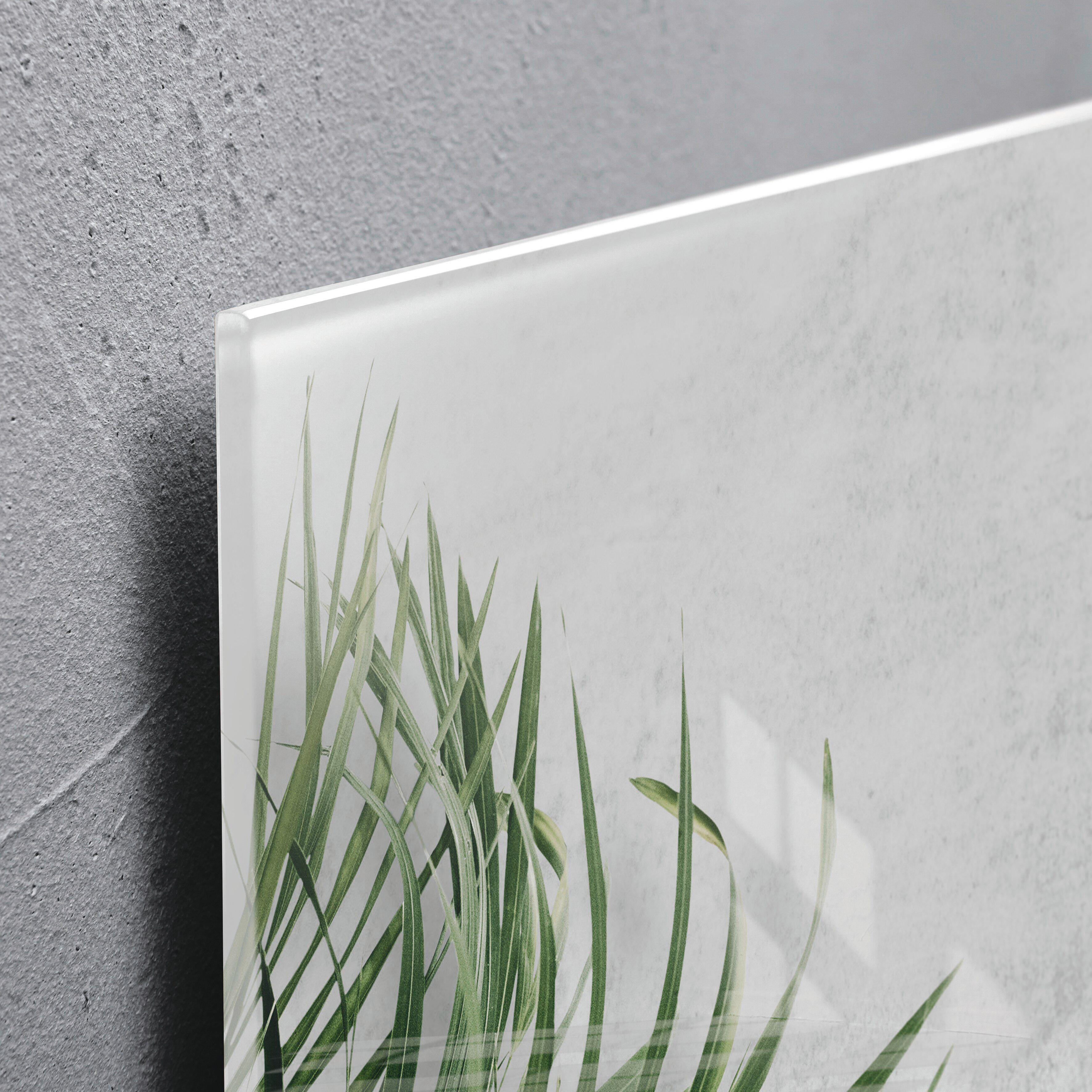 Nahaufnahme einer Wandkunst mit grünem Gras auf weißem Hintergrund. Die linke Seite zeigt eine graue Wand.