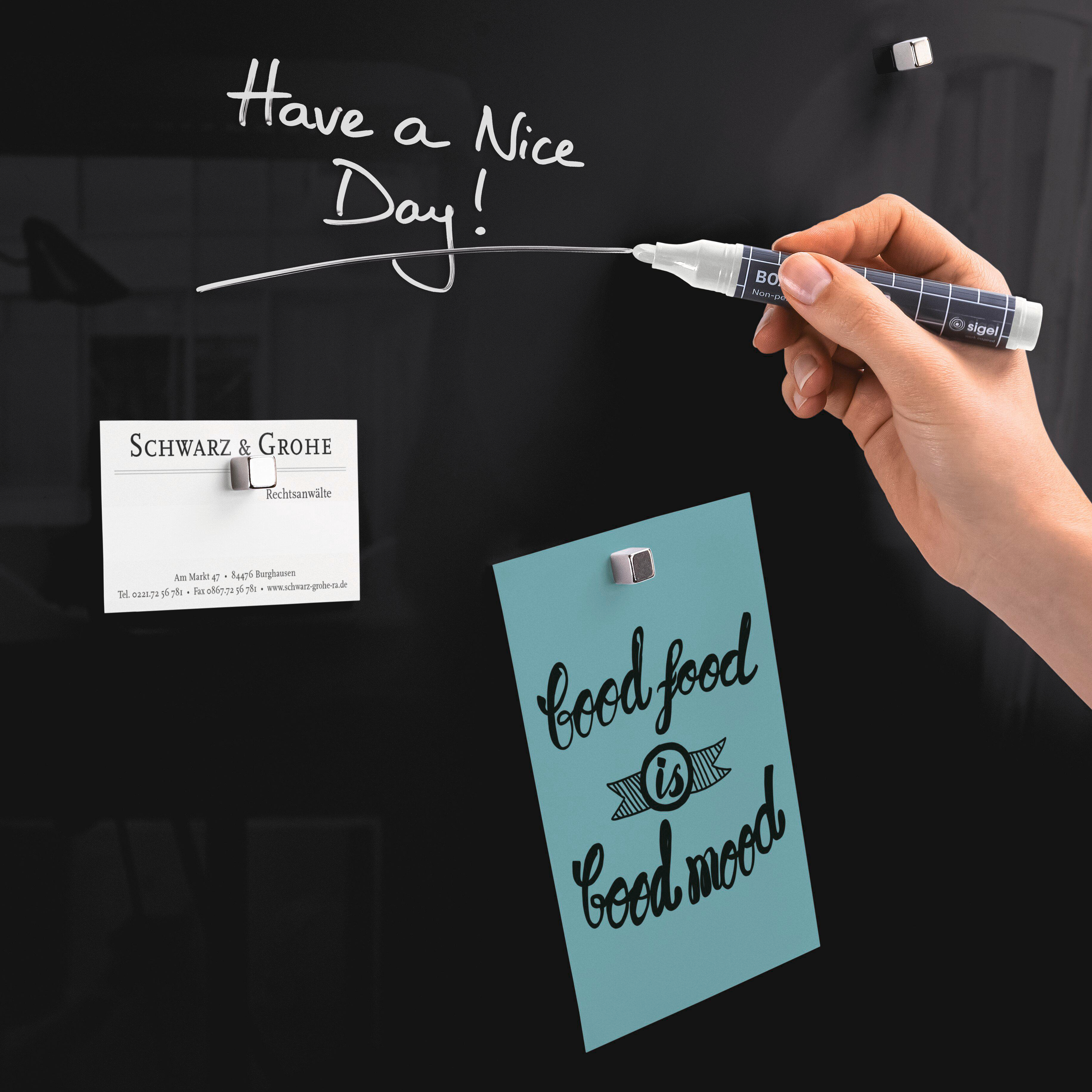 Eine schwarze Tafel mit weißer Schrift: Have a Nice Day! Eine Hand hält einen Stift. Notizen sind angebracht.