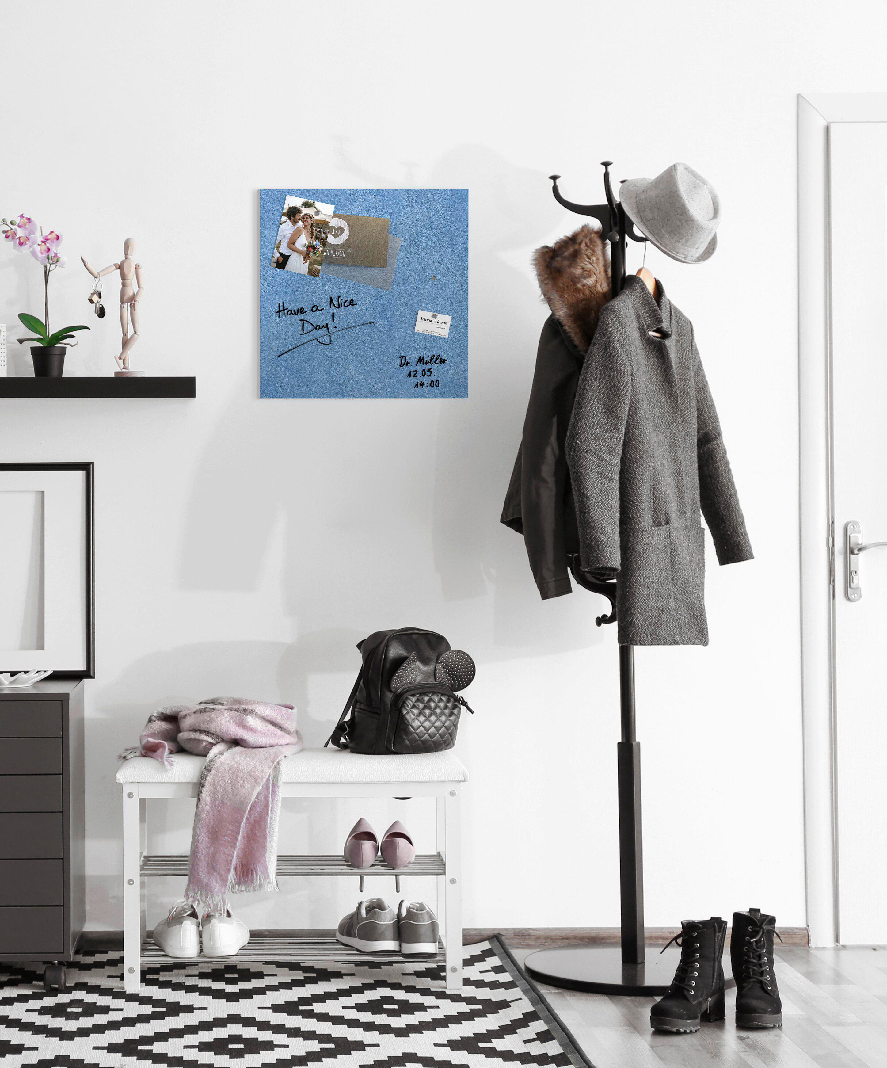 Flur mit Garderobe, Bank und Schuhen. Eine blaue Tafel mit Notiz und Bild hängt an der Wand.