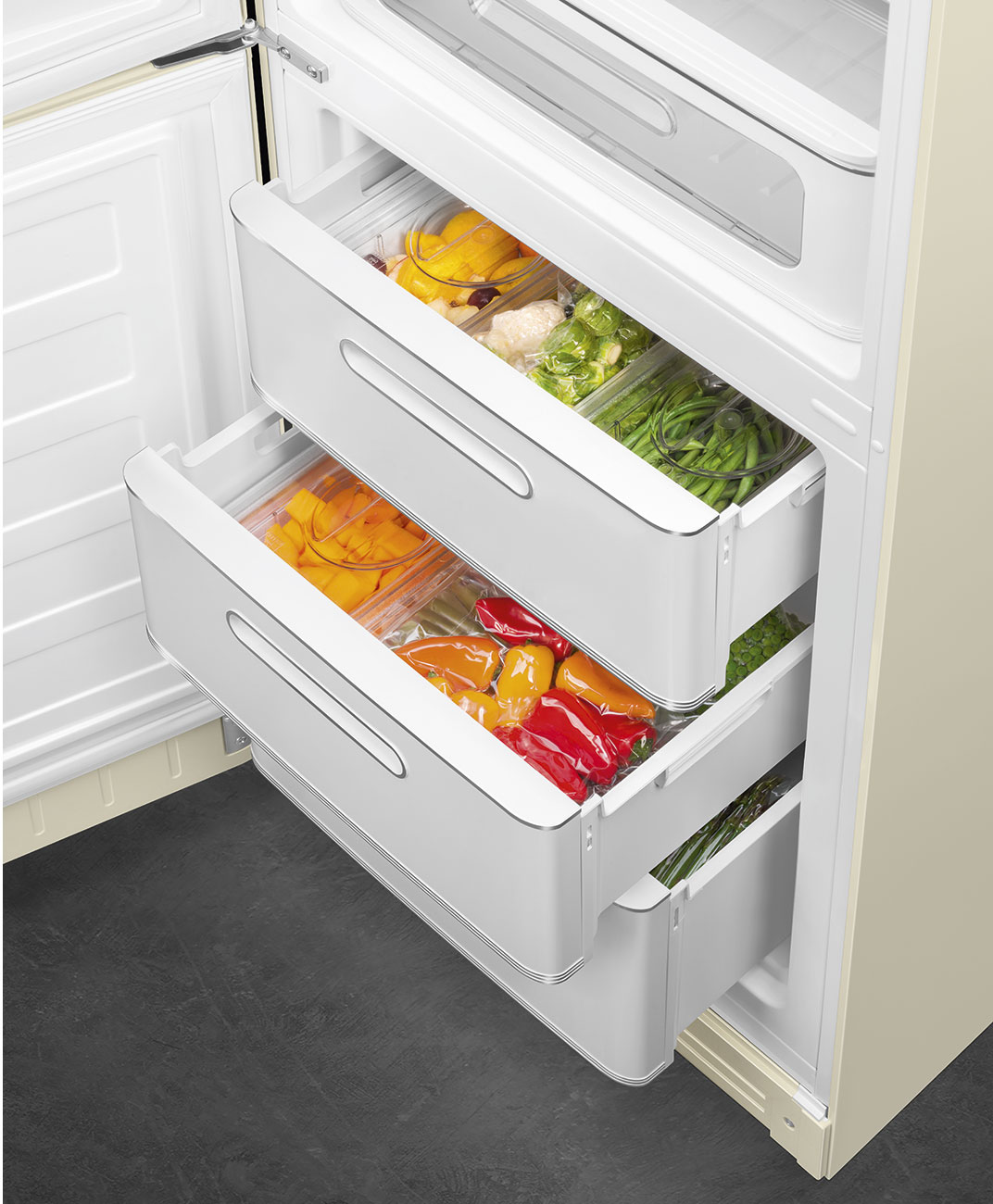 Offener Kühlschrank mit Schubladen voller farbenfrohem Gemüse, darunter Paprika. Beige- und Weißtöne dominieren das Design des Kühlschranks.