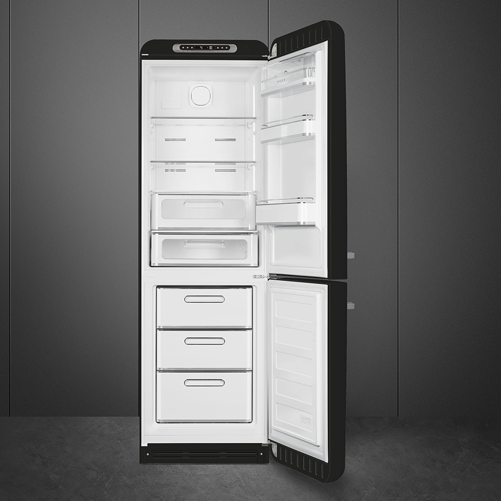 Offener schwarzer Kühlschrank. Innenraum mit weißen Regalen und Schubladen. Grauer Wandhintergrund und grauer Boden. Tür offen.
