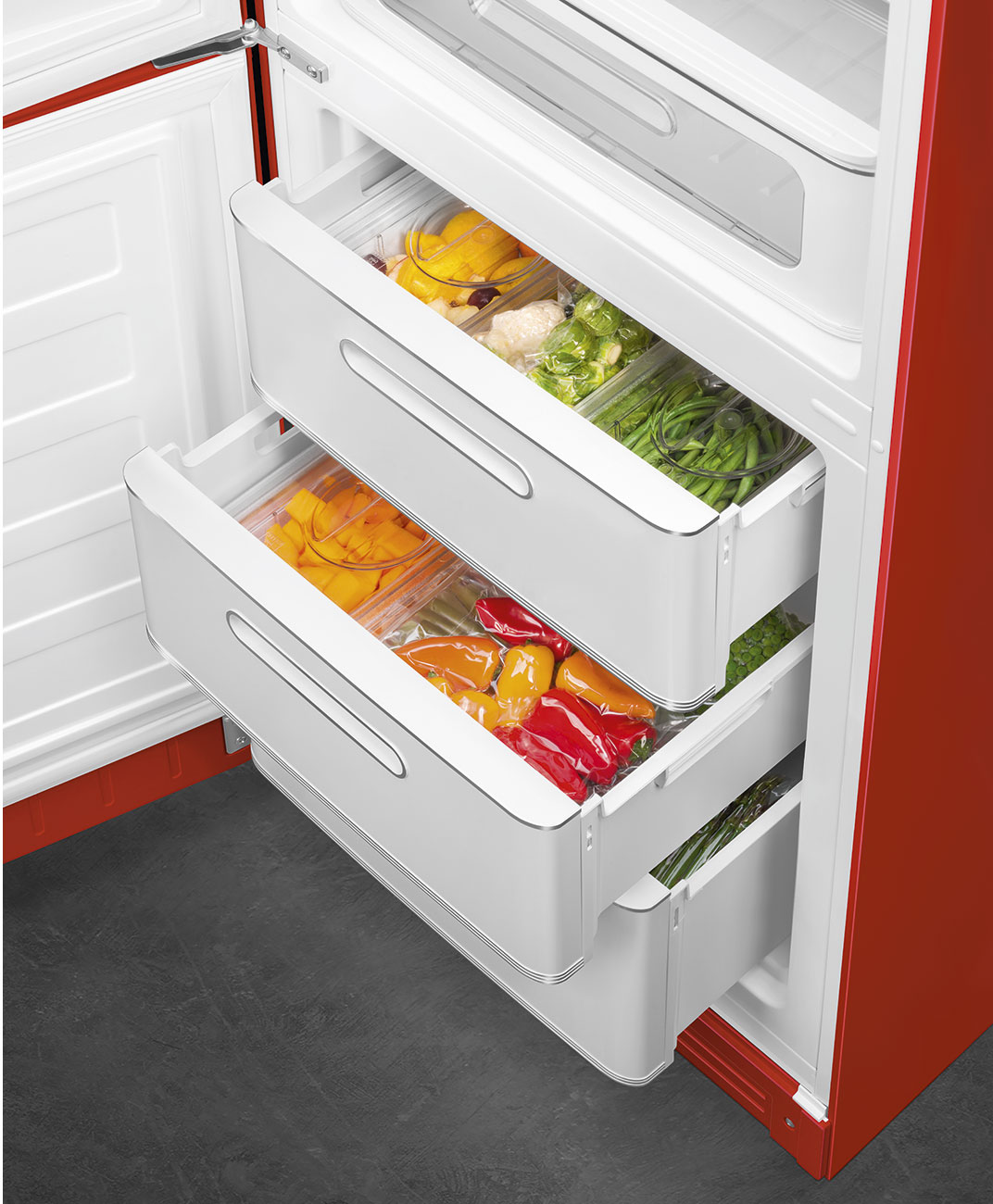 Offener roter Kühlschrank mit weißen Schubladen, gefüllt mit verpackten gelben, orangen und roten Paprika, grünen Bohnen und anderem Gemüse.