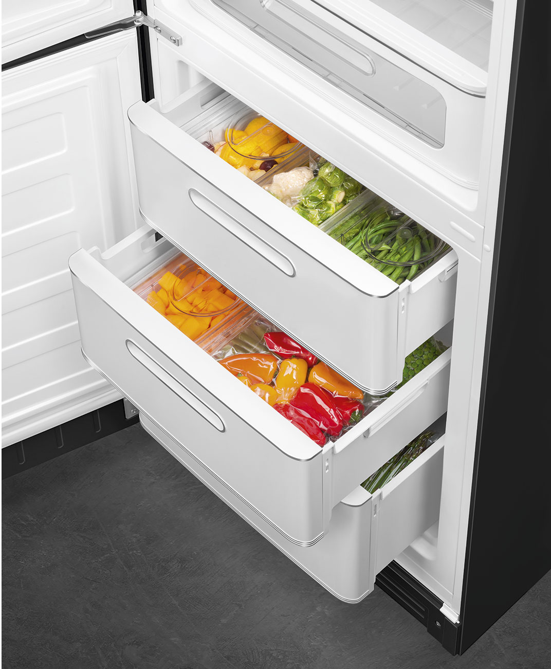 Offener Kühlschrank mit Schubladen. Paprika, Bohnen und anderes Gemüse sind sichtbar. Weiße Schubladen und schwarzer Kühlschrank.