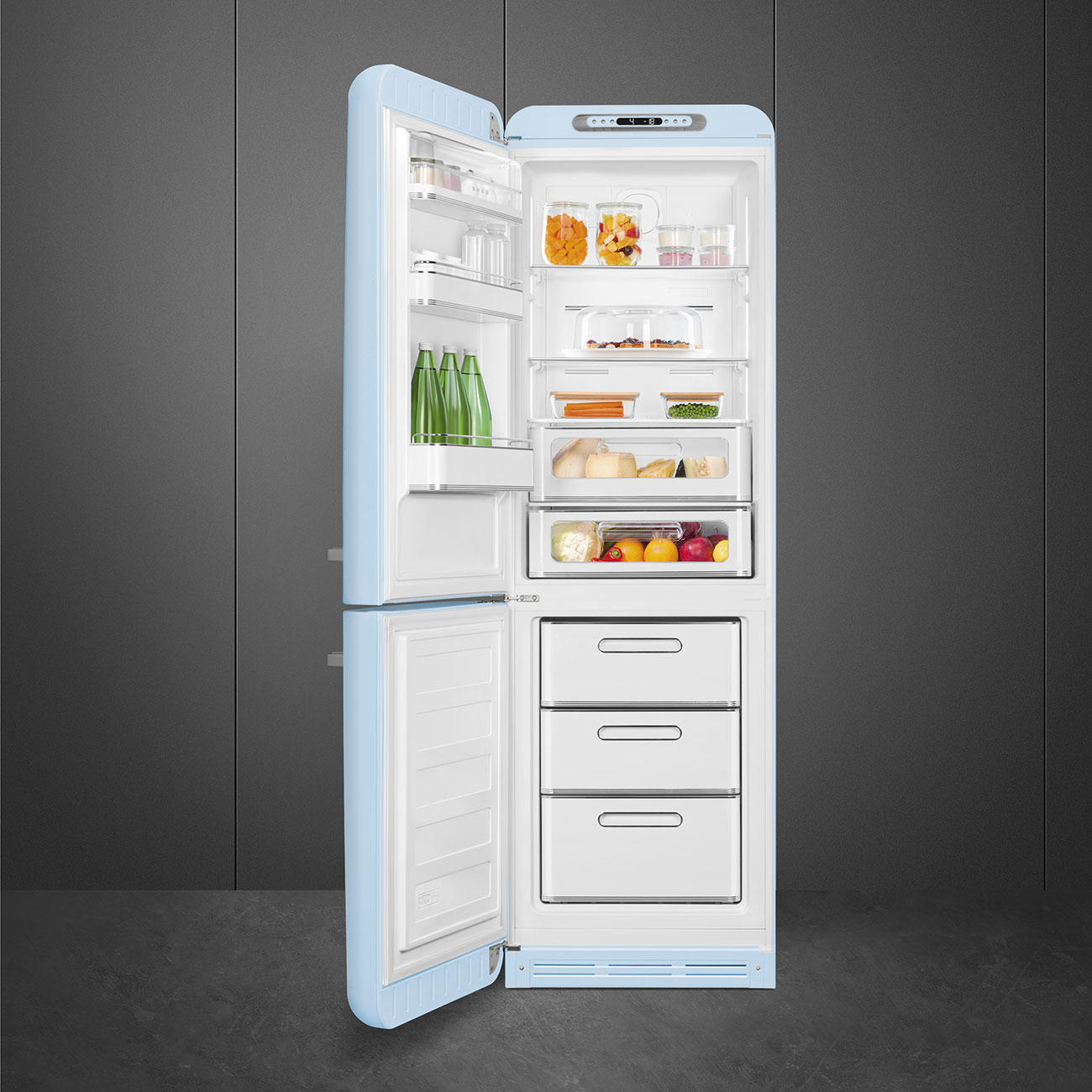 Offener, hellblauer Kühlschrank mit Lebensmitteln gefüllt. Enthält Gläser, Obst, Gemüse und Flaschen. Graue Wand im Hintergrund.