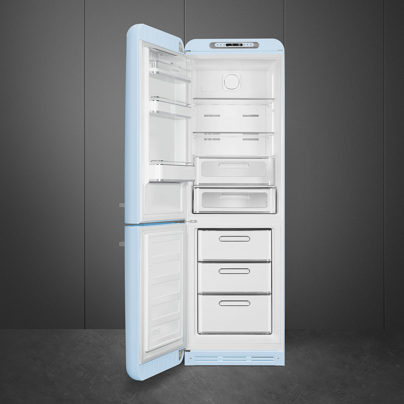 Offener, hellblauer Retro-Kühlschrank vor grauer Wand. Innenraum mit Regalen und Schubladen, leer.