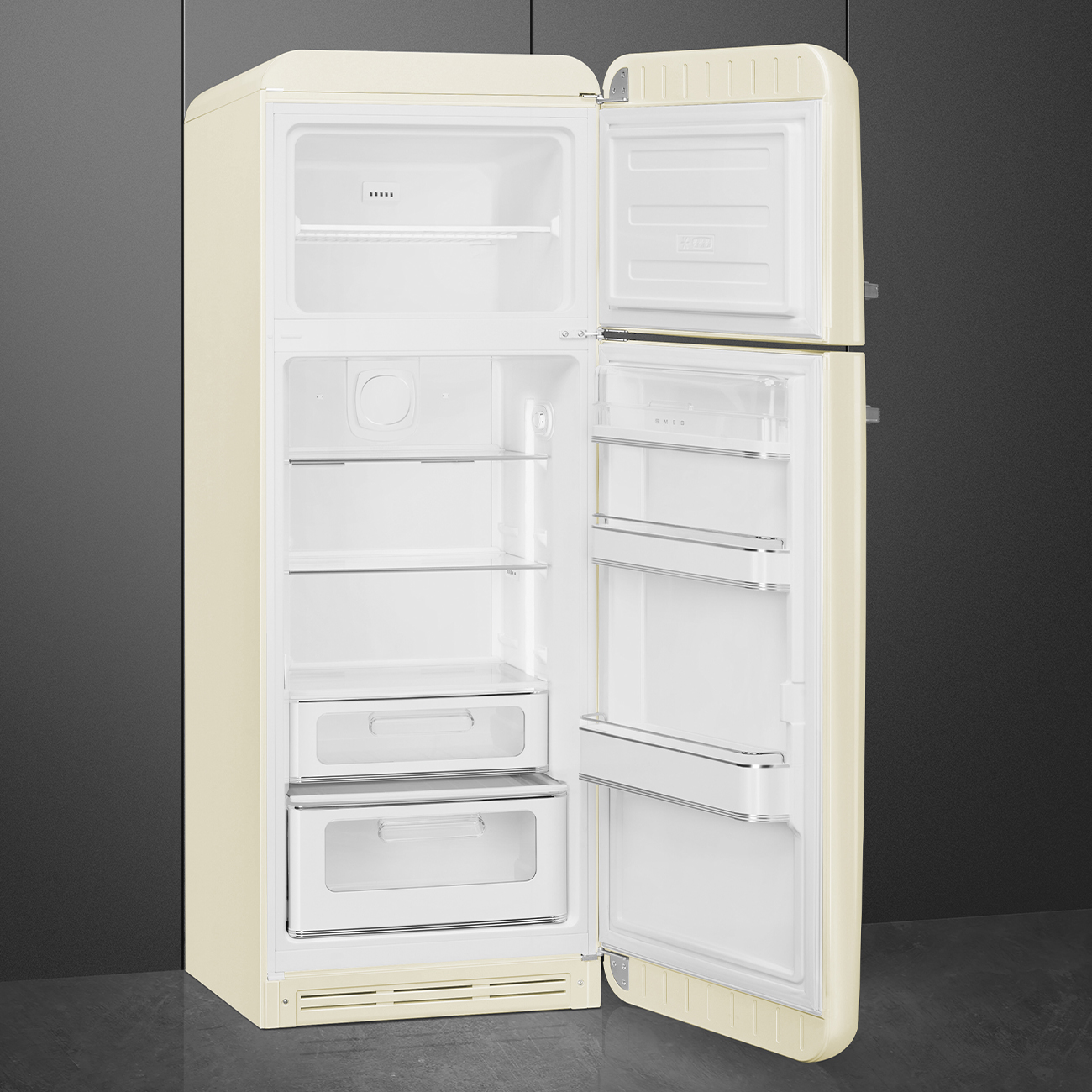 Offener cremefarbener Vintage-Kühlschrank. Oberer Teil ist Gefrierfach, unterer Teil hat Regale und Schubladen. Grauer Wandhintergrund, grauer Boden.