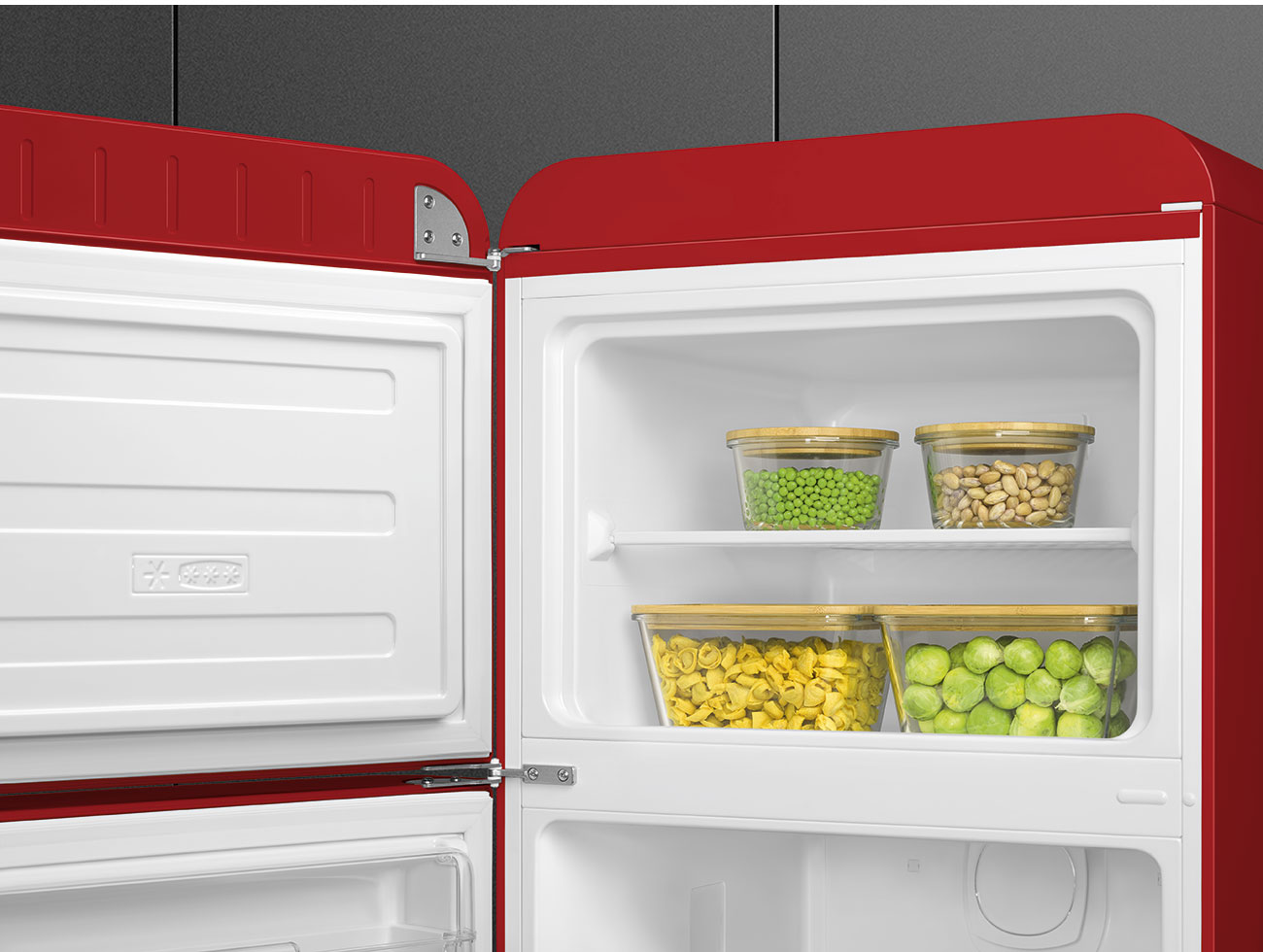 Roter Kühlschrank geöffnet mit Essen. Erbsen, Bohnen, Tortellini und Rosenkohl in Glasbehältern auf Regalen.