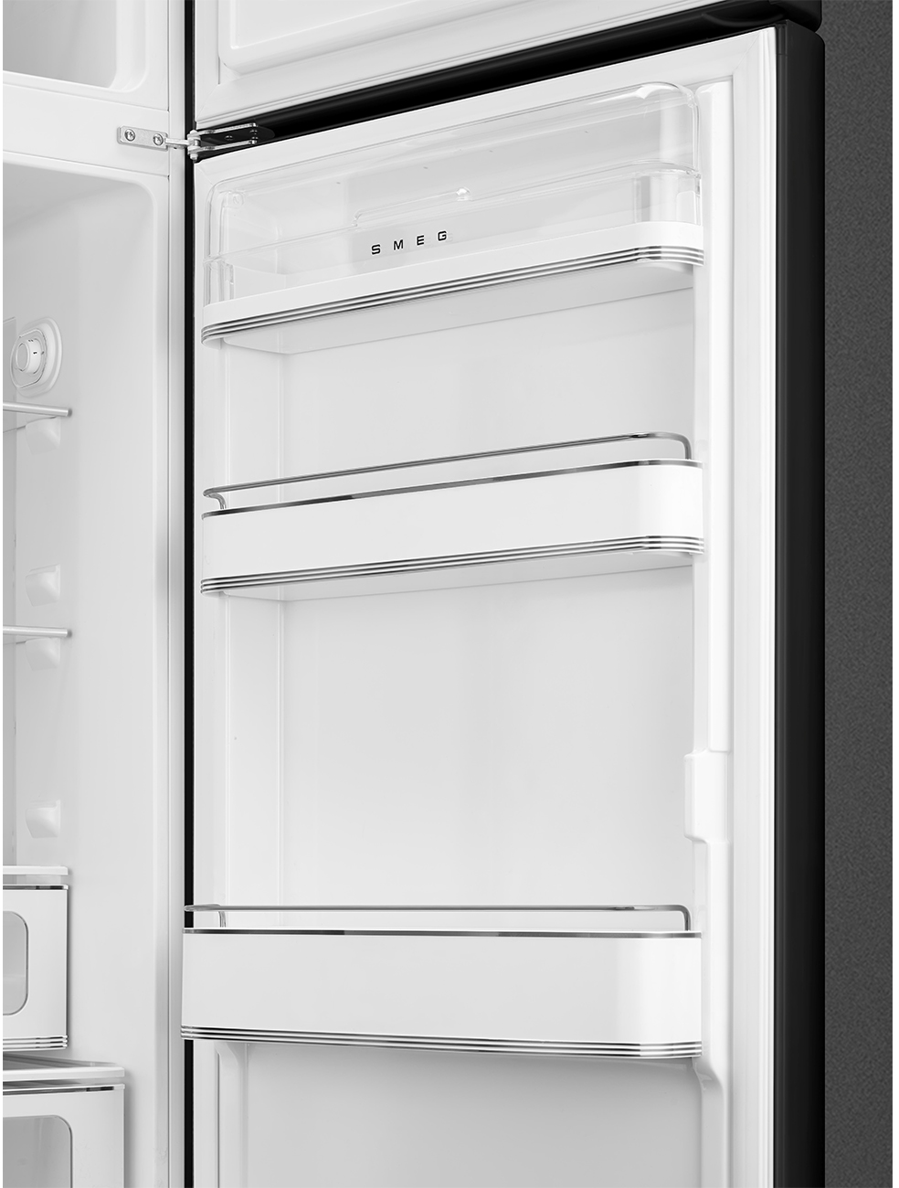 Innenraum eines offenen weißen Kühlschranks. Er hat Regale und ein oberes Regal aus klarem Kunststoff. Das SMEG-Logo ist sichtbar. Die Tür ist offen.