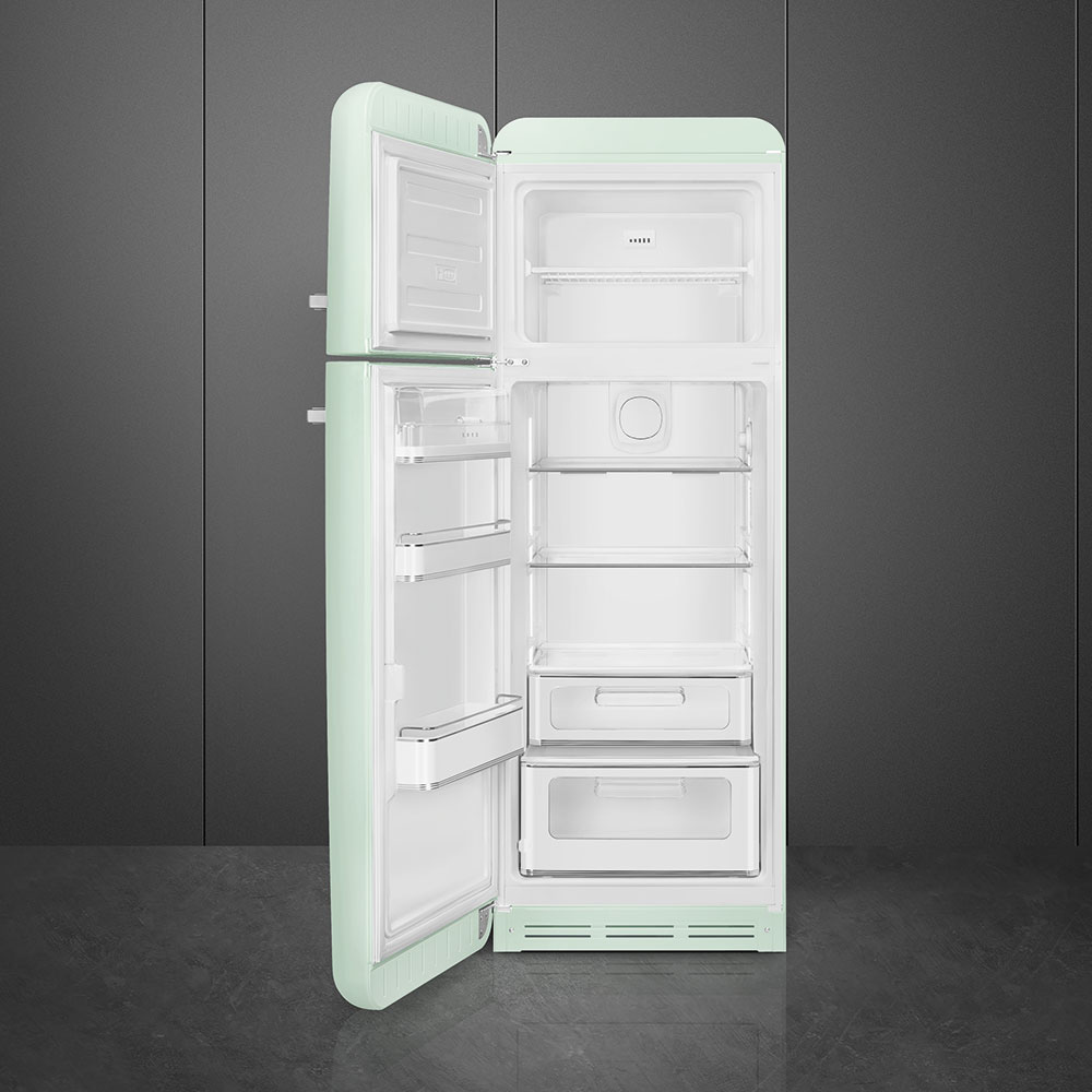 Offener, mintgrüner Retro-Kühlschrank. Die Tür ist geöffnet und gibt Regale und Schubladen frei. Graue Wand im Hintergrund, dunkler Boden.