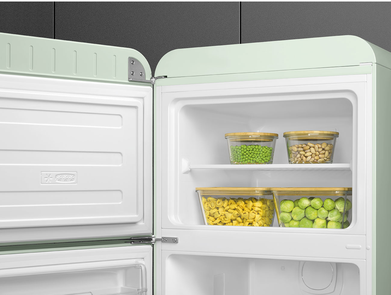 Offener Kühlschrank mit Behältern mit Erbsen, Bohnen, Tortellini und Rosenkohl. Der Kühlschrank ist mintgrün.
