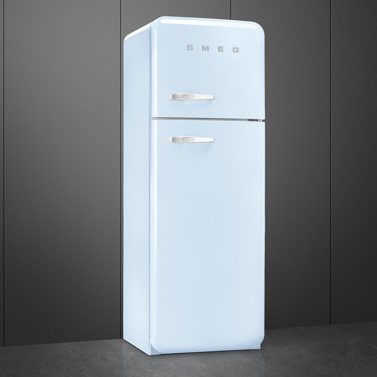 Ein hellblauer SMEG-Kühlschrank steht vor einem dunkelgrauen Hintergrund. Er hat zwei Türen und Chromgriffe. Der Boden ist grau.