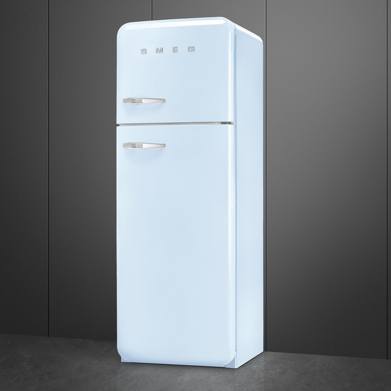 Ein hellblauer SMEG-Kühlschrank steht vor einem dunkelgrauen Hintergrund. Der Kühlschrank hat zwei Türen und Chromgriffe.