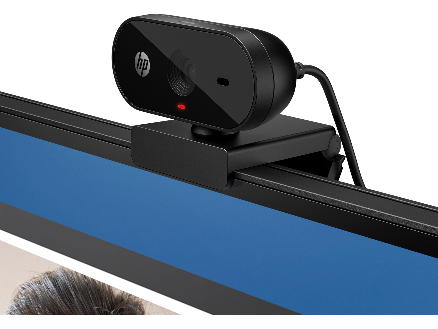 Eine schwarze HP-Webcam ist auf einem Monitor montiert. Die Webcam hat ein rotes Licht und ein Objektiv. Der Monitor zeigt einen blauen Bildschirm.