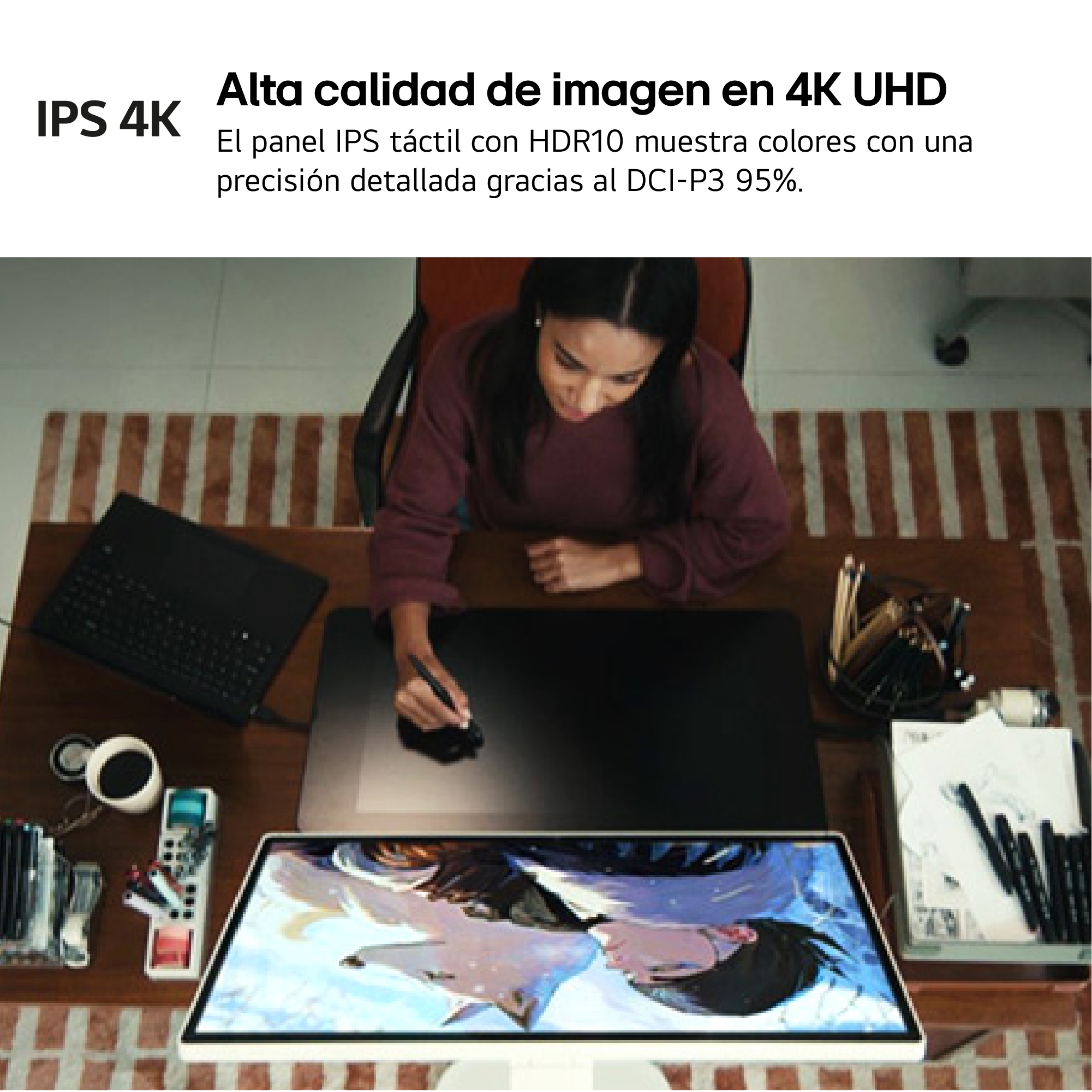 Mujer dibujando en una tableta. En el escritorio de madera hay una computadora portátil, un monitor y útiles de arte. El fondo tiene un diseño de ladrillo.