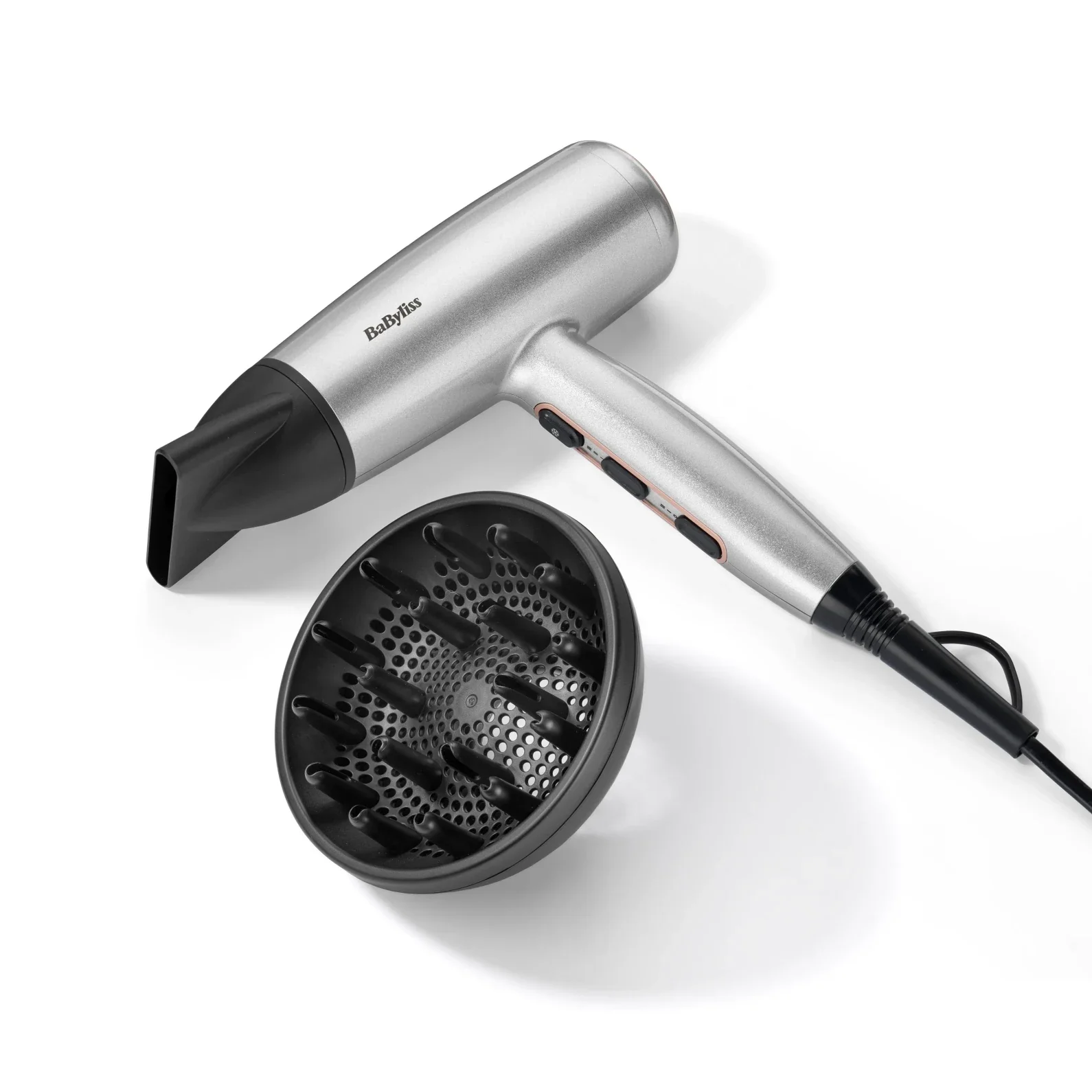 Ezüst hajszárító fekete fúvókával és fekete diffúzorral fehér háttéren. A márka a Babyliss.