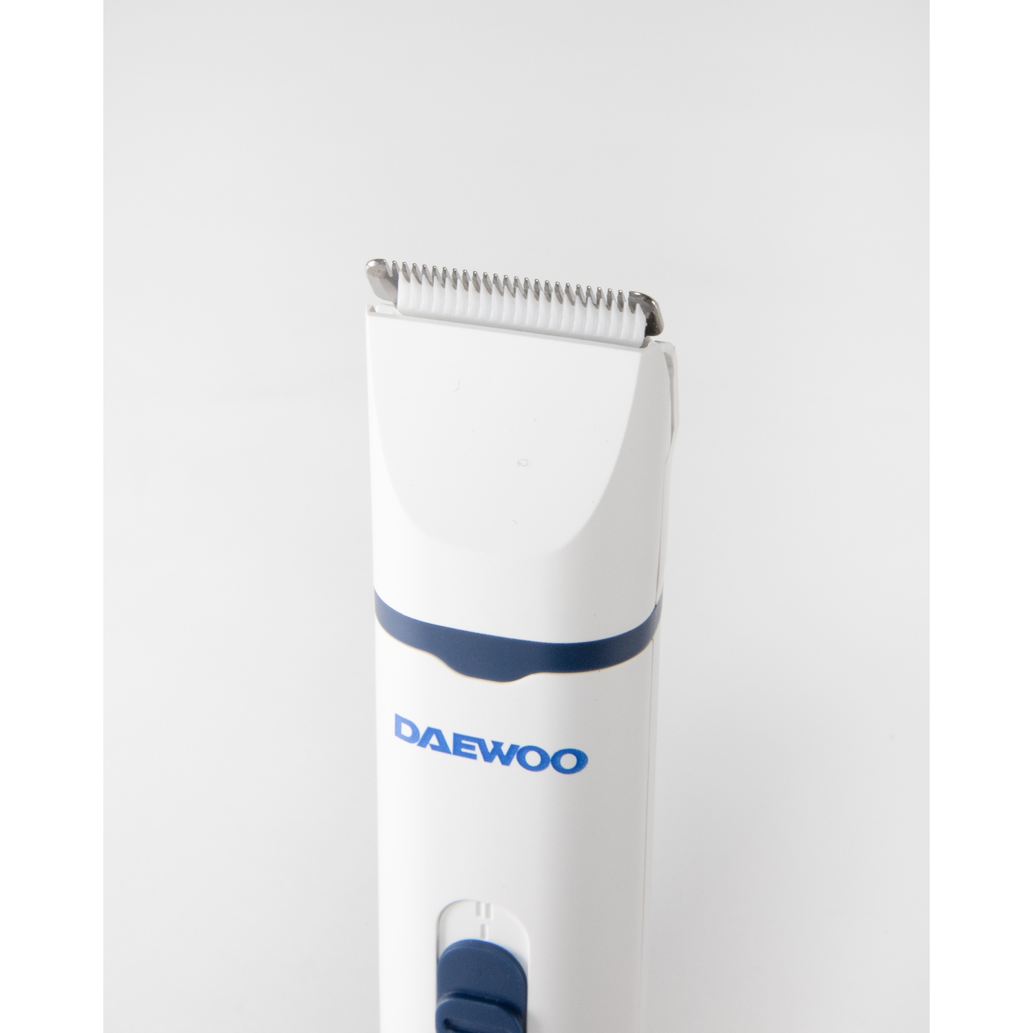 Un tagliacapelli Daewoo bianco con una striscia e un bottone blu. La lama è argentata, lo sfondo è bianco.