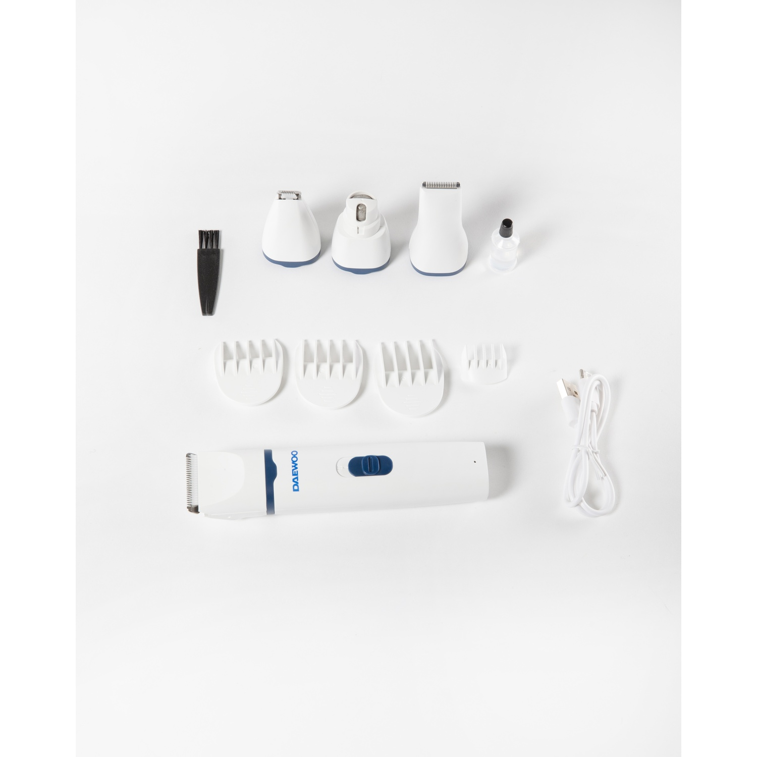 Un kit per la cura personale con un trimmer bianco e blu, accessori, un pennello, una piccola bottiglia e un cavo USB, tutto su una superficie bianca.