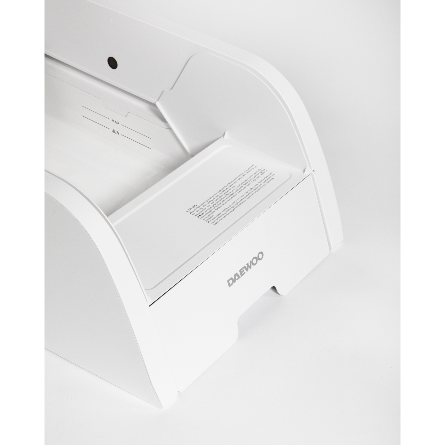 Un componente bianco di un elettrodomestico Daewoo con marcature MAX e MIN, un'etichetta di avvertimento e un design curvo.
