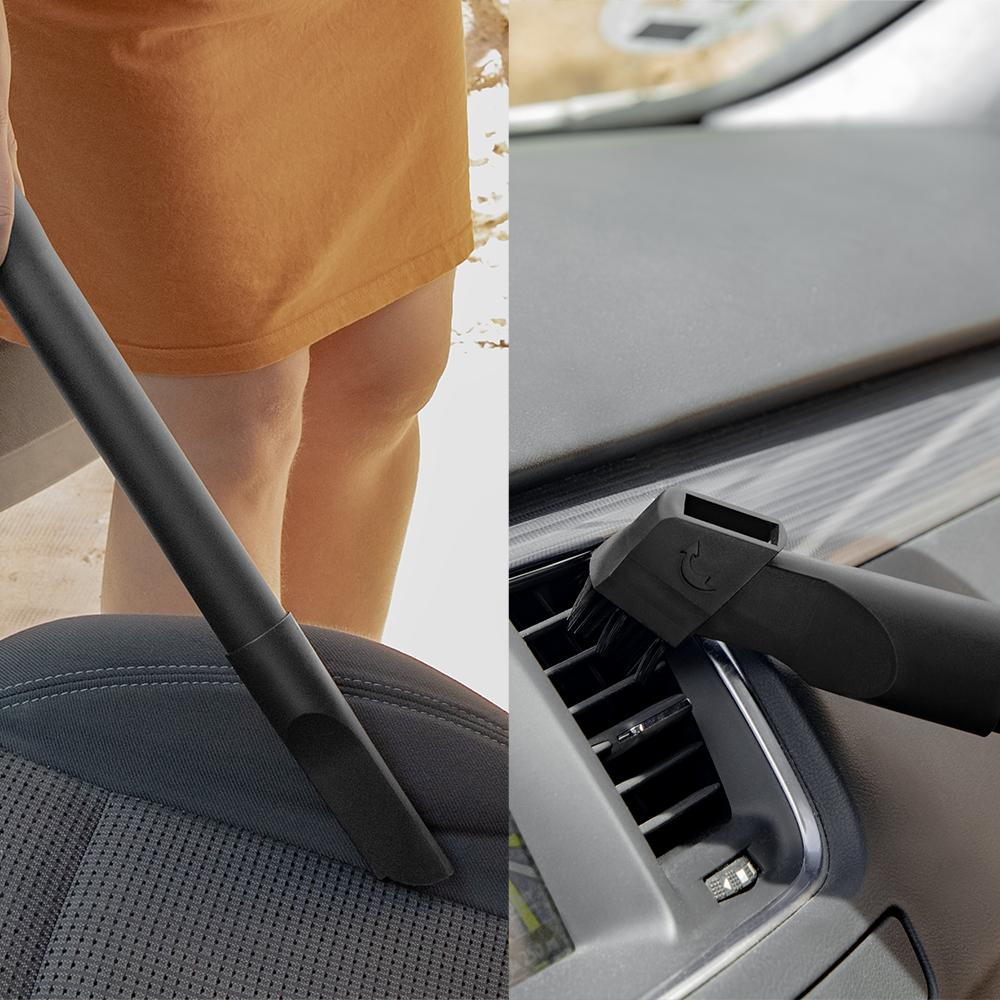 Una persona aspira el interior de un coche. Una manguera negra de aspiradora limpia el asiento a la izquierda y el salpicadero a la derecha.