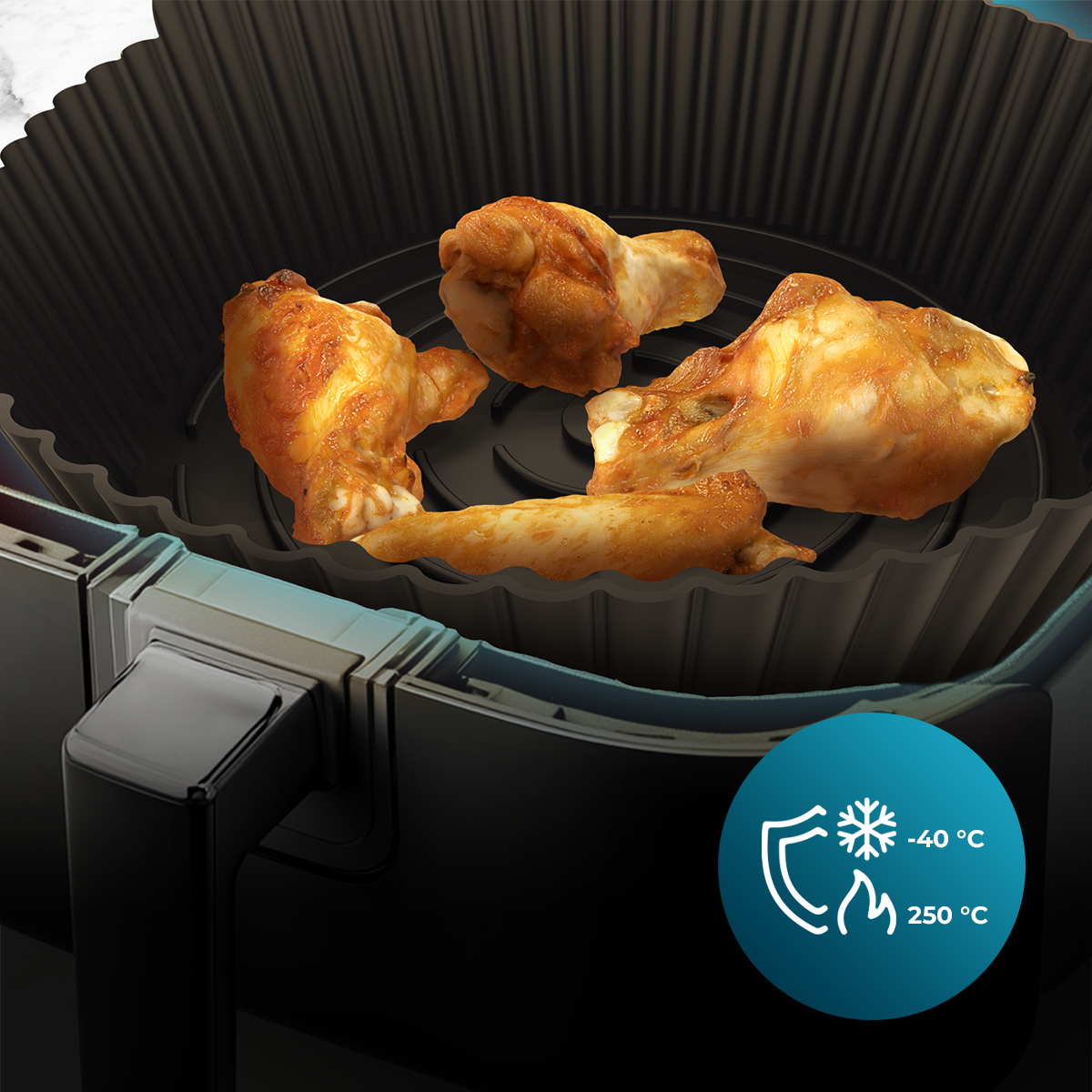 Alitas de pollo en una freidora de aire. Las alitas son doradas. La freidora es negra con un icono de temperatura azul.