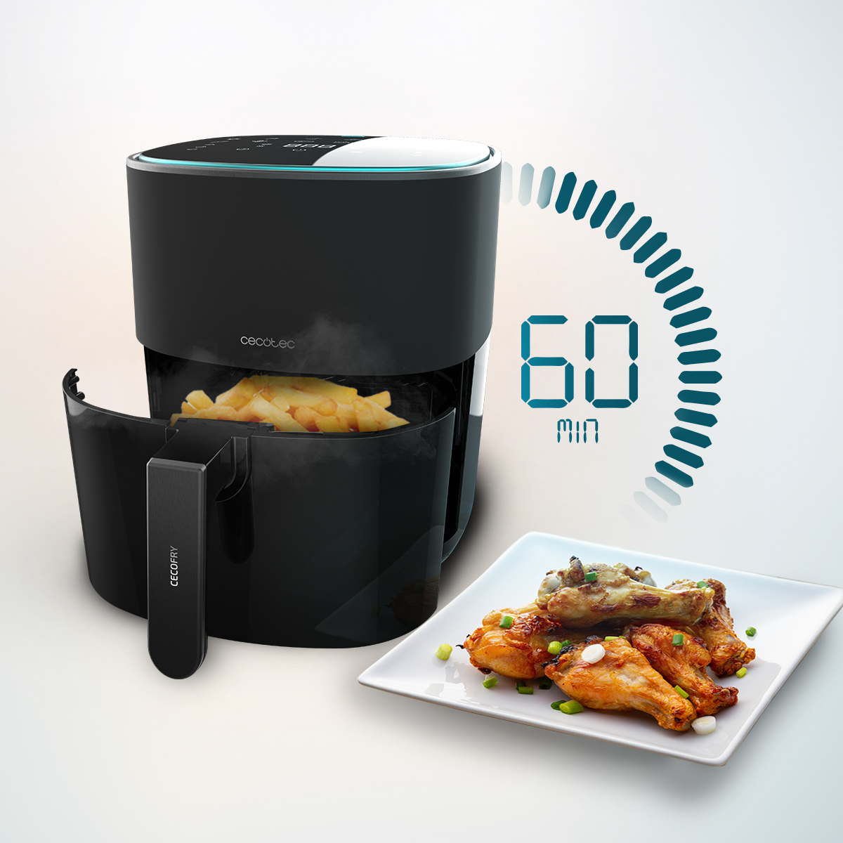 Freidora de aire negra con patatas fritas. Alitas de pollo en plato. Temporizador muestra 60 minutos.