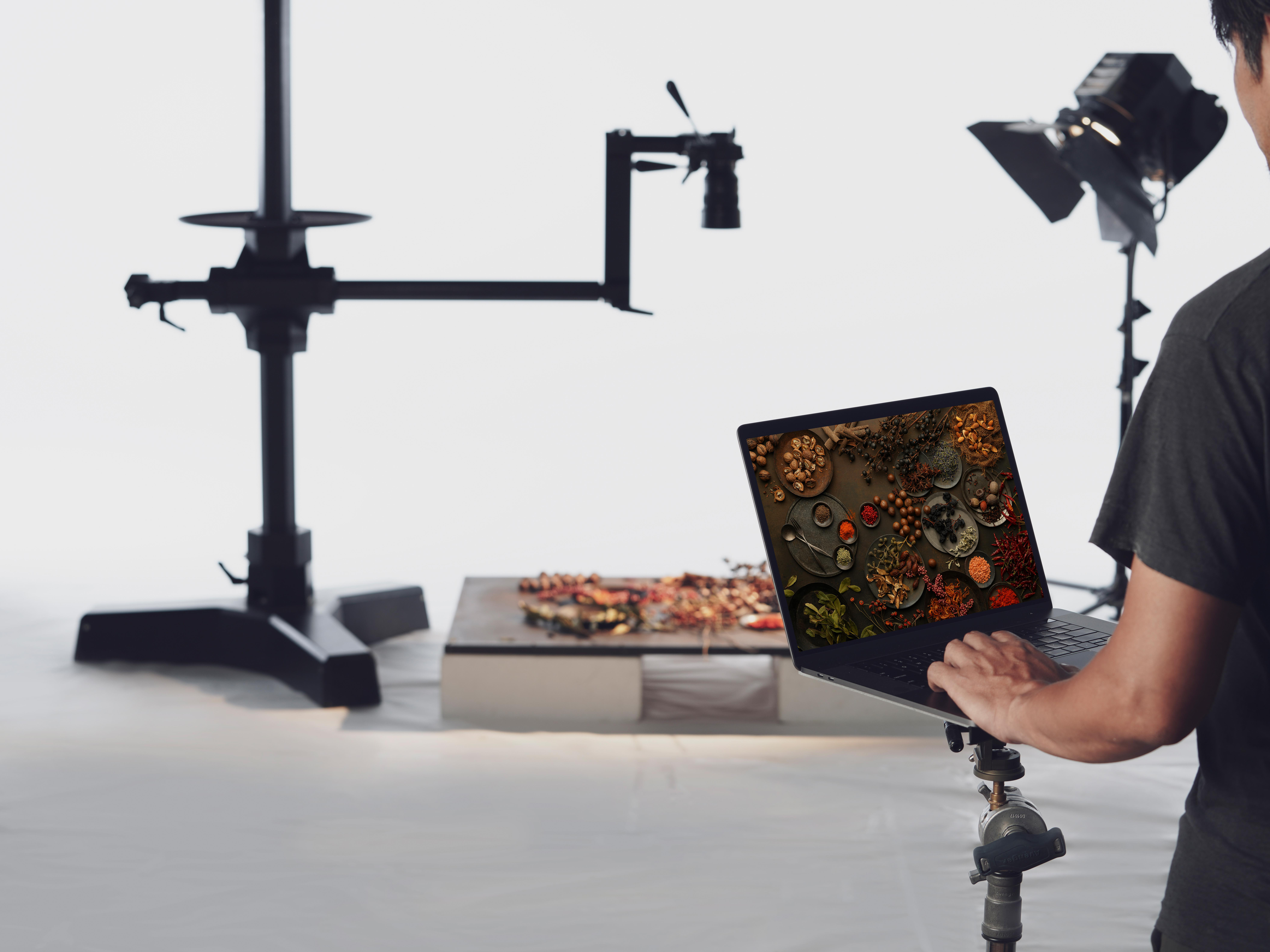 Eine Person benutzt einen Laptop. Der Bildschirm zeigt Essen. Studio-Setup mit Beleuchtung und Ausrüstung im Hintergrund.