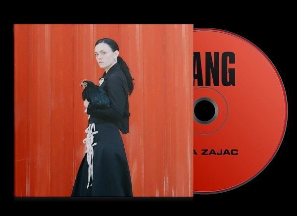 Frau in schwarzem Kleid hält ein Huhn, neben einem CD-Case mit dem Titel 'ANG' und dem Künstler 'A Zajac'.