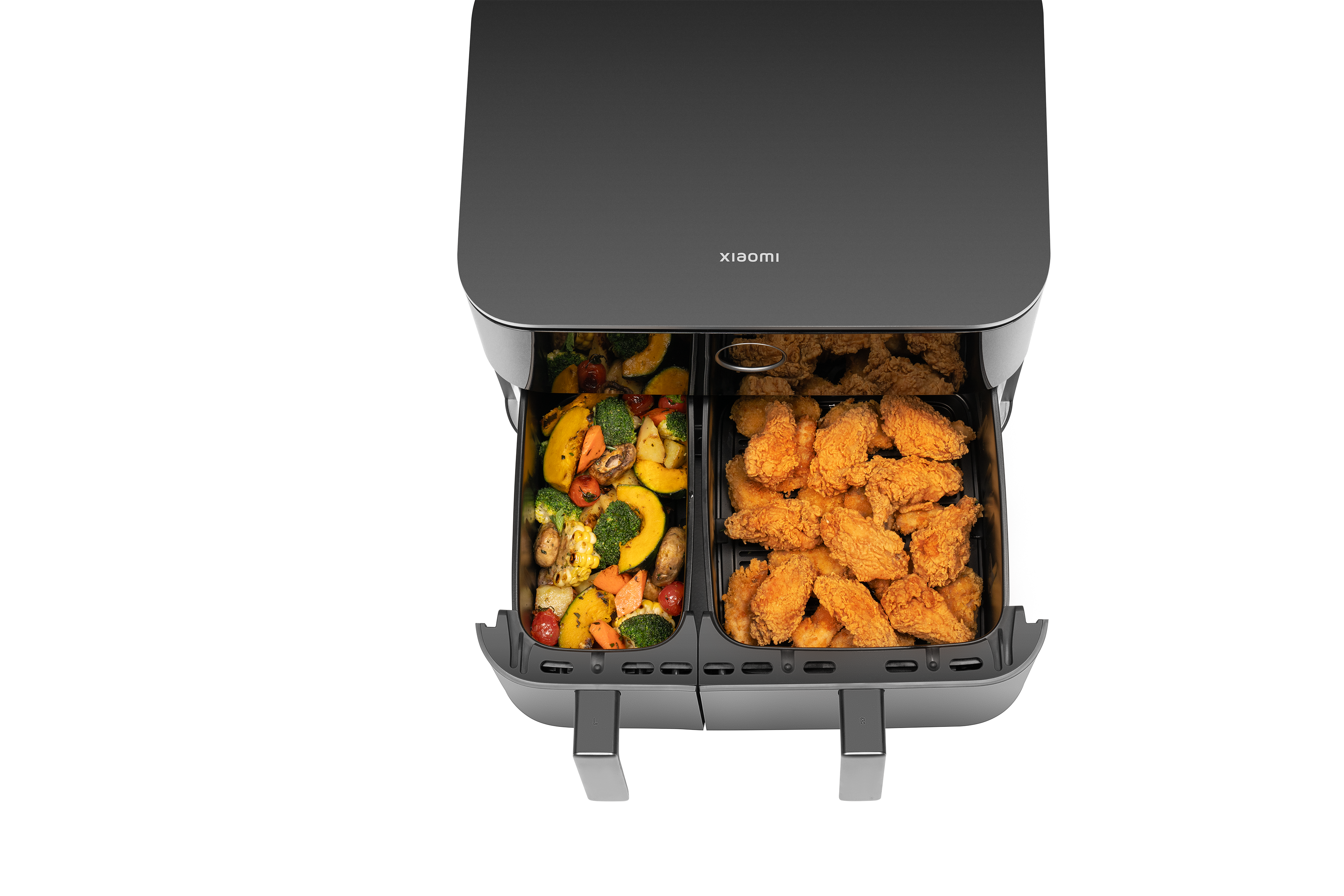 Ein Airfryer mit geröstetem Gemüse links und frittierten Chicken Wings rechts.