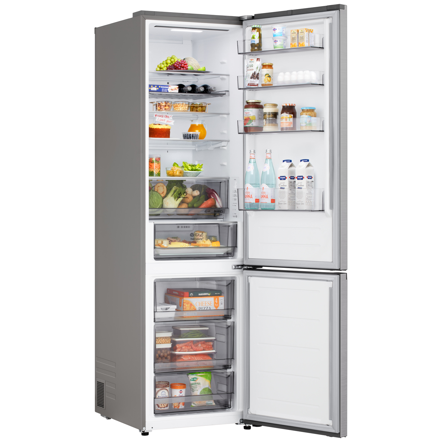 Open refrigerator filled with food: fruits, drinks, vegetables, and frozen items. Victoria cake note on the top shelf.