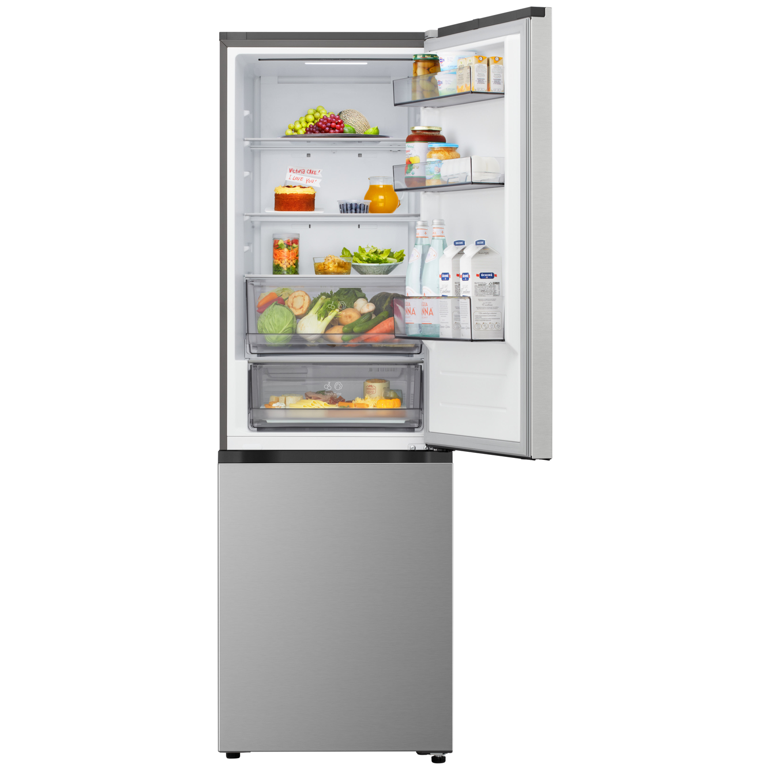 Open refrigerator showing contents: fruits, vegetables, juice, milk, jars, cake. Stainless steel exterior with bottom freezer.