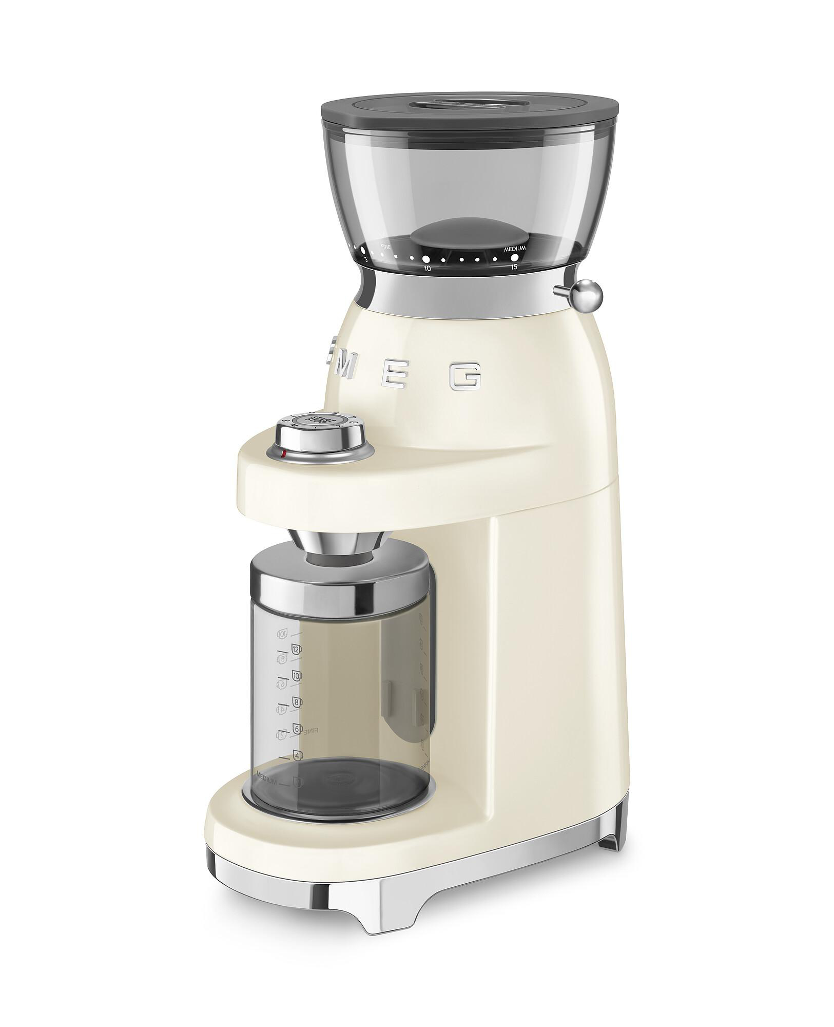 Cremefarbene SMEG Kaffeemühle. Sie hat einen transparenten Bohnenbehälter und einen Glasbehälter für Kaffeepulver. Akzente aus Edelstahl.