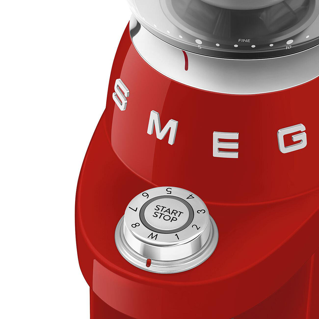 Rotes SMEG-Gerät mit Zifferblatt, Zahlen und den Worten 'START STOP'. Die Oberseite hat einen transparenten Behälter mit Feineinstellungen.
