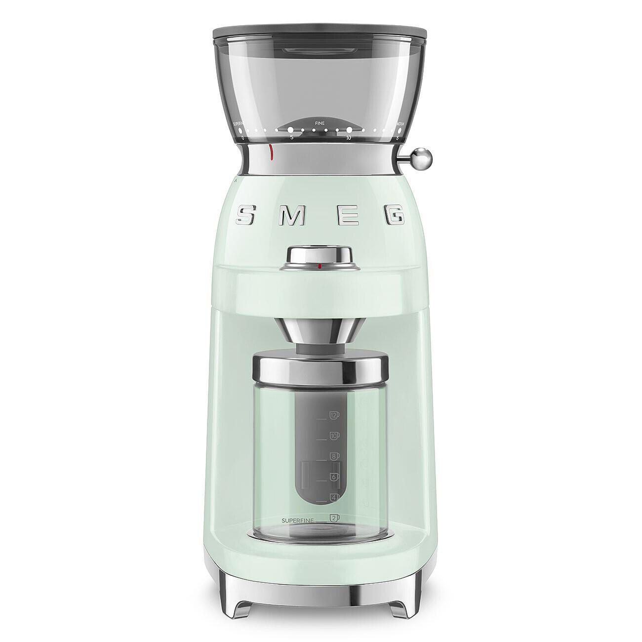 Eine mintgrüne Smeg Kaffeemühle. Sie hat einen transparenten Bohnenbehälter und einen Glasbehälter für Kaffeepulver. Sie hat einen Chromfuß.