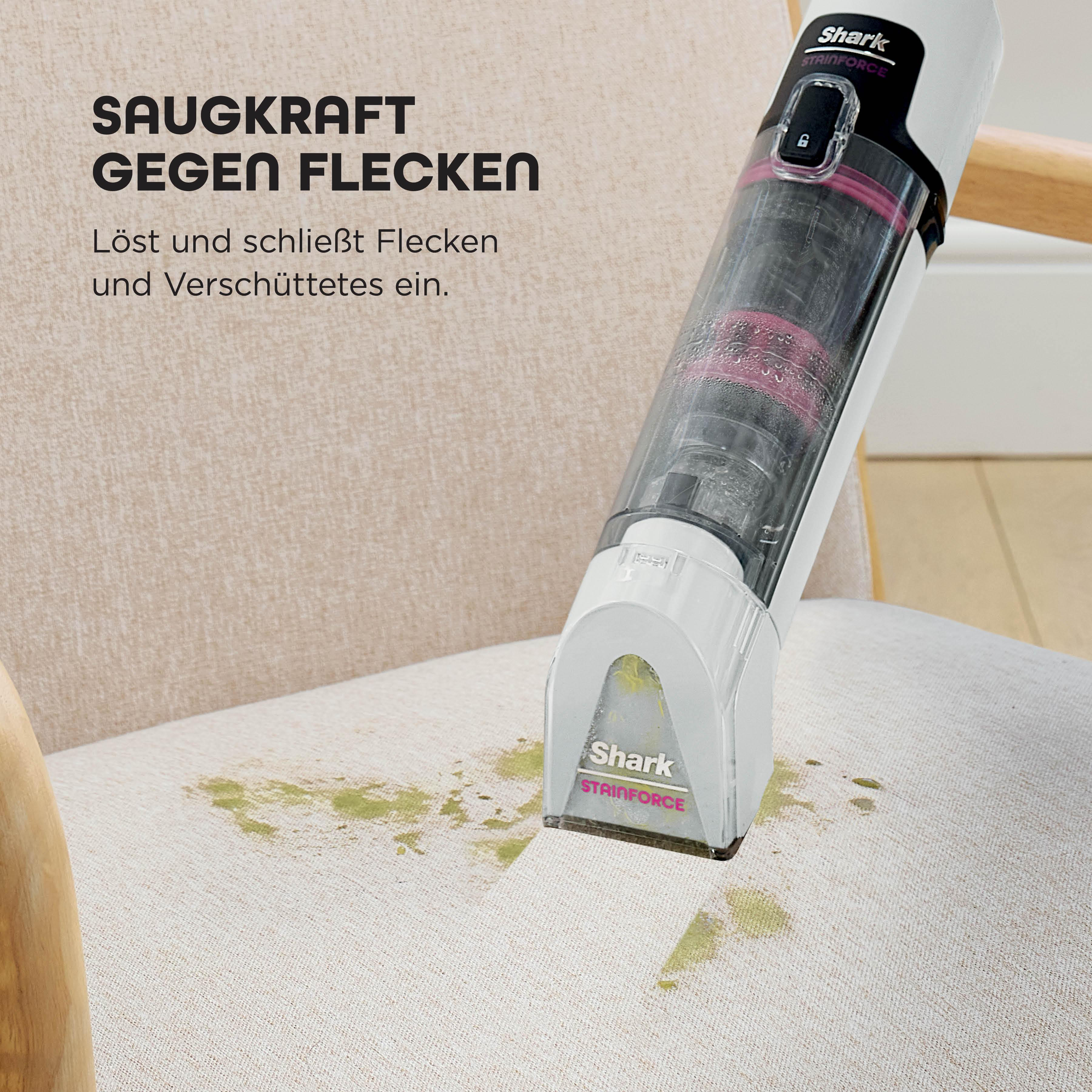 Ein Shark Stainforce-Staubsauger reinigt einen Fleck auf einem beigen Stuhl. Der Text lautet 'Saugkraft gegen Flecken'.