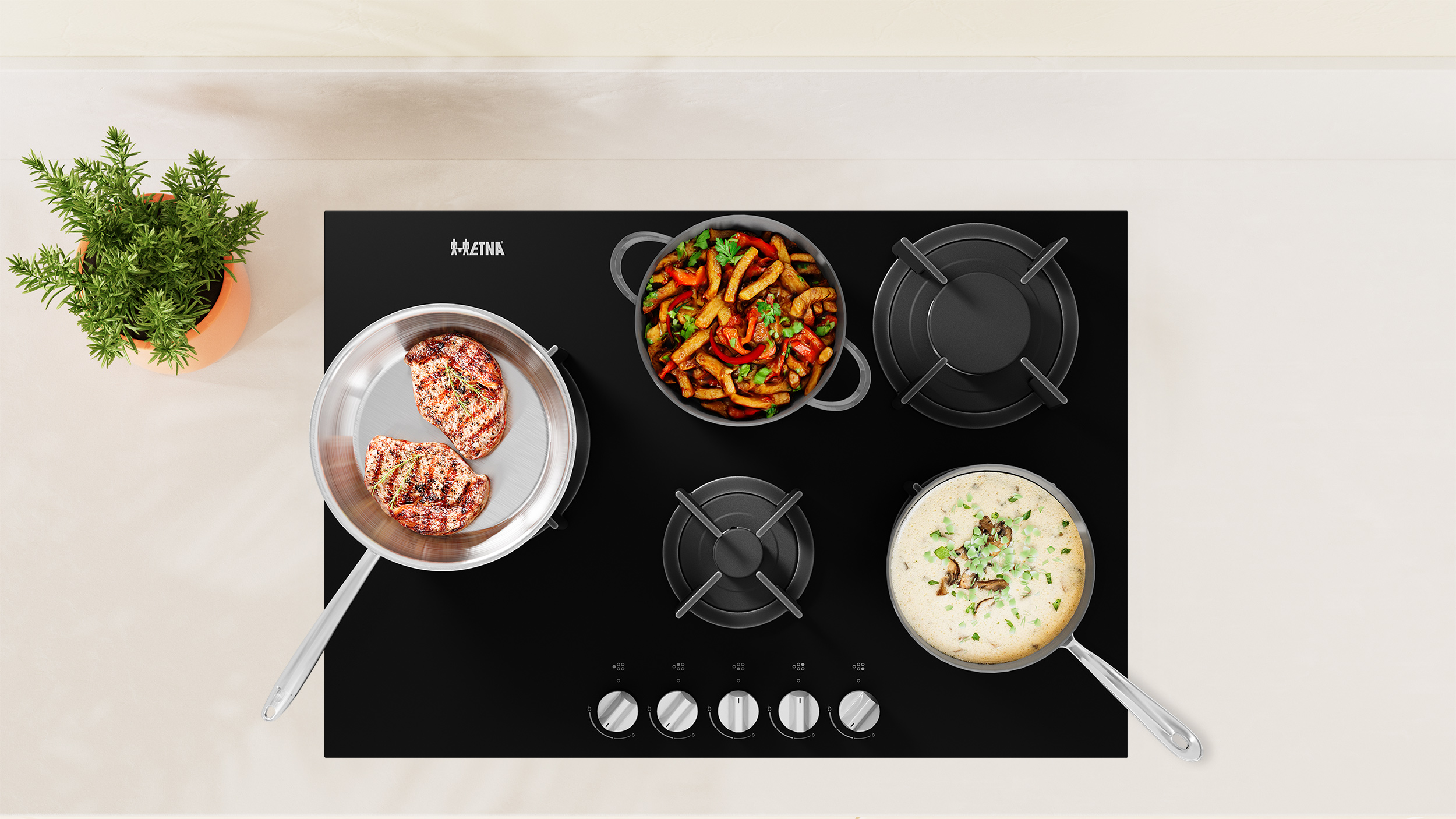 Overhead view of a black stovetop with food in pans, including grilled steak and vegetables, with a potted plant.