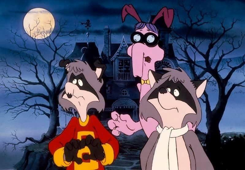 Zeichentrickszene: Zwei Waschbären und ein rosa, kaninchenartiger Charakter vor einem unheimlichen Haus unter Vollmond.