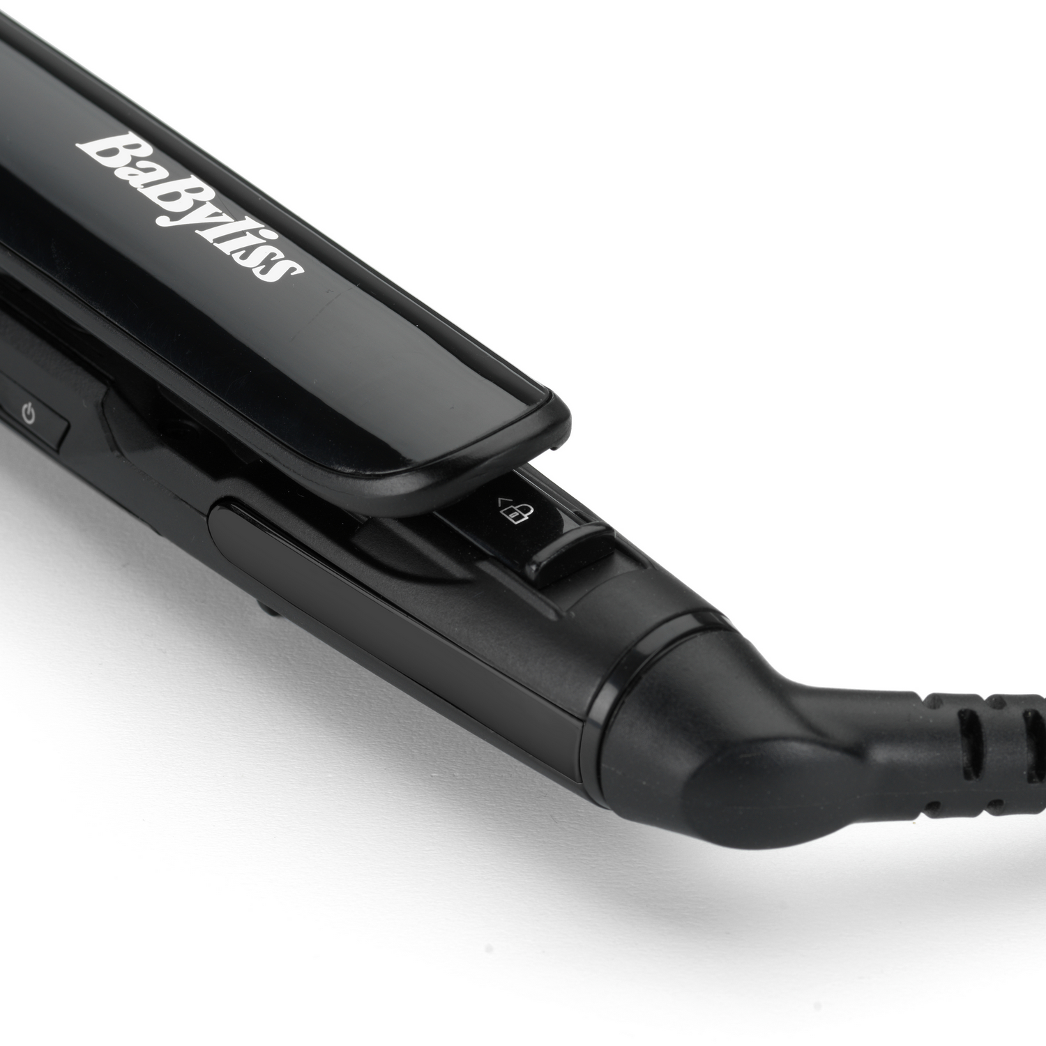 Primer plano de una plancha de pelo negra BaByliss. El dispositivo está sobre una superficie blanca, con un botón de encendido y un símbolo de candado visible.