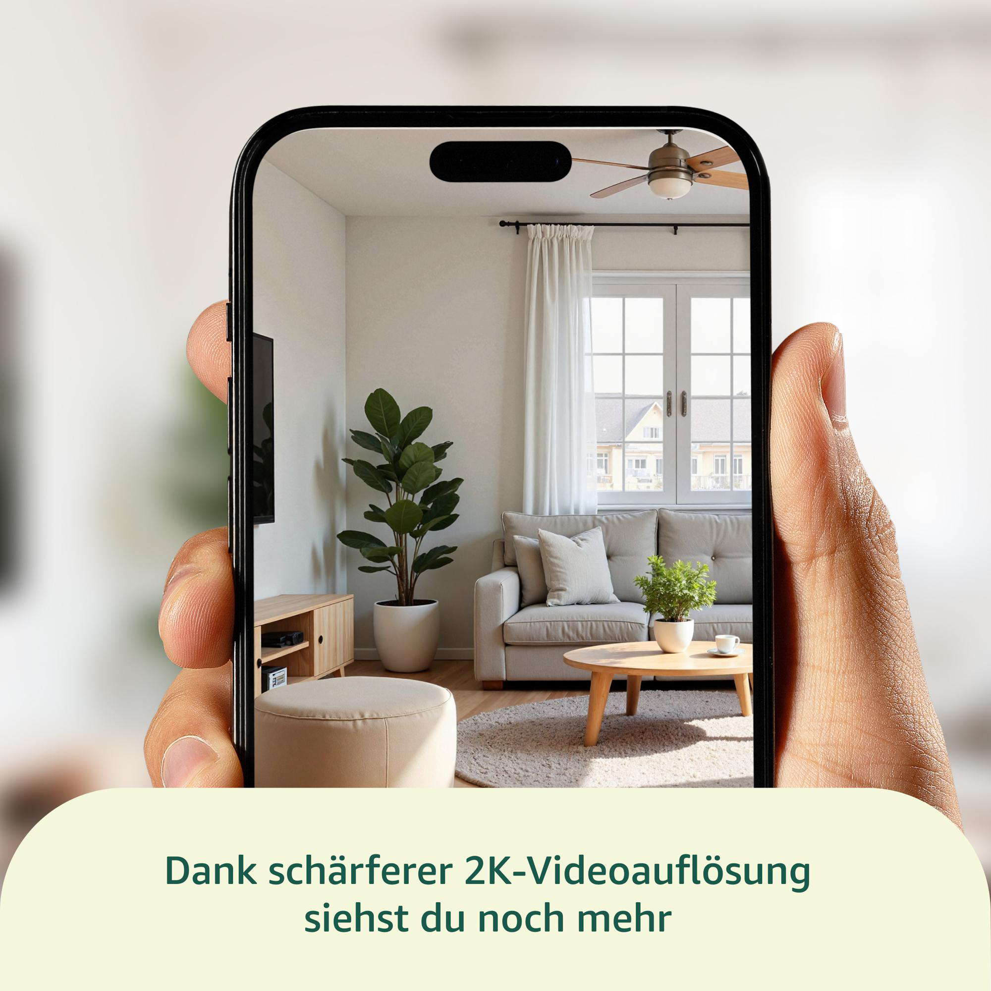 Ein Telefon zeigt ein Wohnzimmer. Hand, die das Telefon hält. Beinhaltet Sofa, Pflanze, Tisch und ein Fenster.