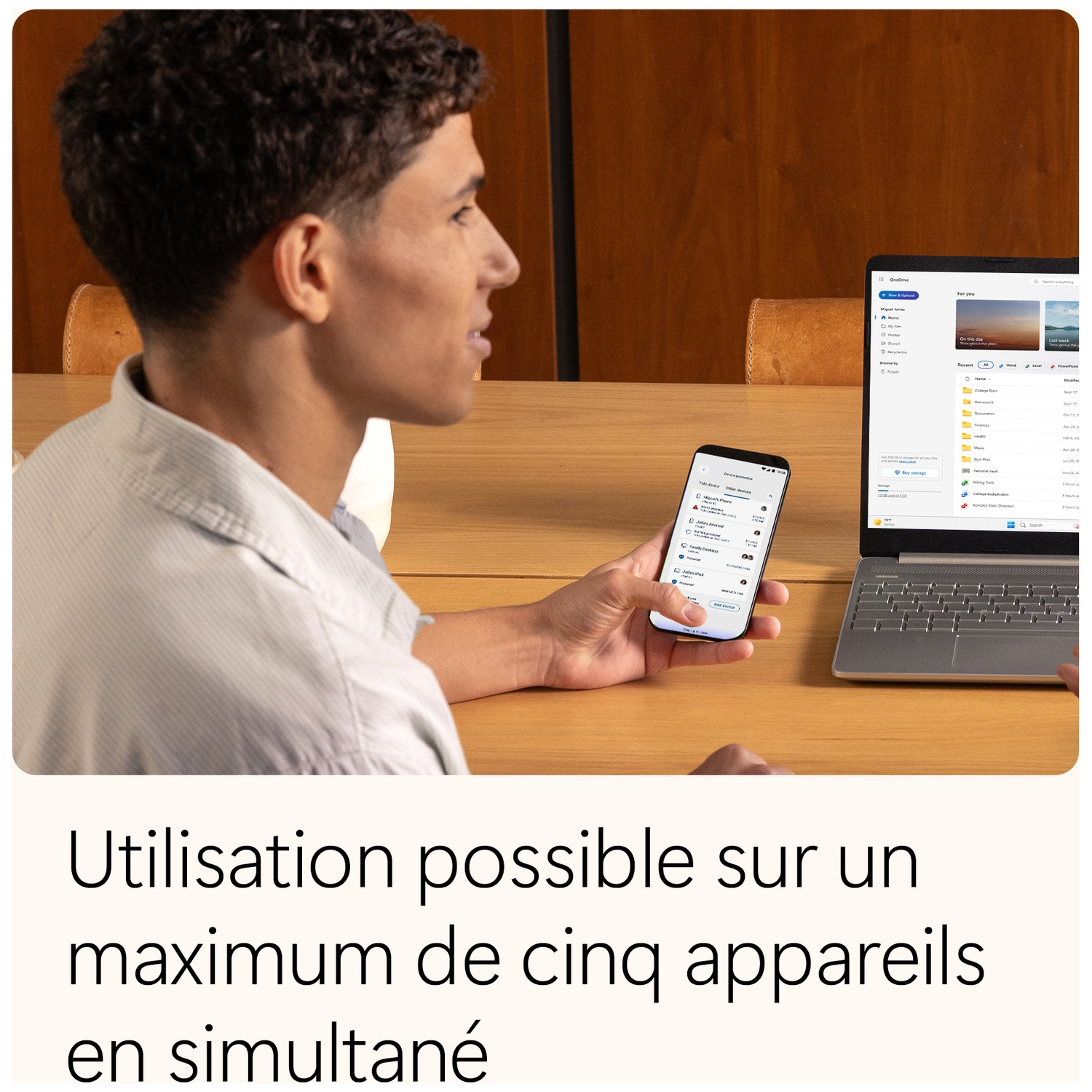 Un homme utilise un ordinateur portable et un téléphone simultanément. L'ordinateur affiche un document, le téléphone une liste.