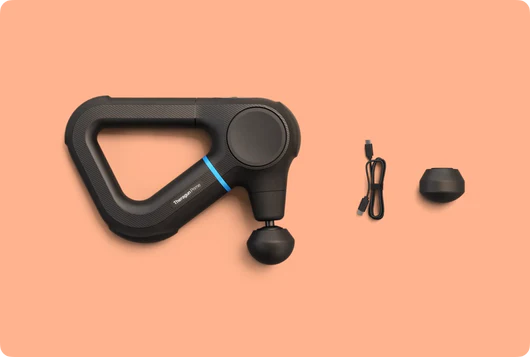 Eine schwarze Massagepistole mit Zubehör: ein Ladekabel und ein runder Aufsatz, auf orangefarbenem Hintergrund.