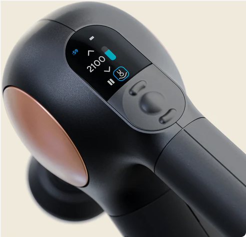 Eine schwarze und graue Massagepistole mit digitaler Anzeige. Sie hat einen kupferfarbenen Akzent. Der Hintergrund ist cremefarben.