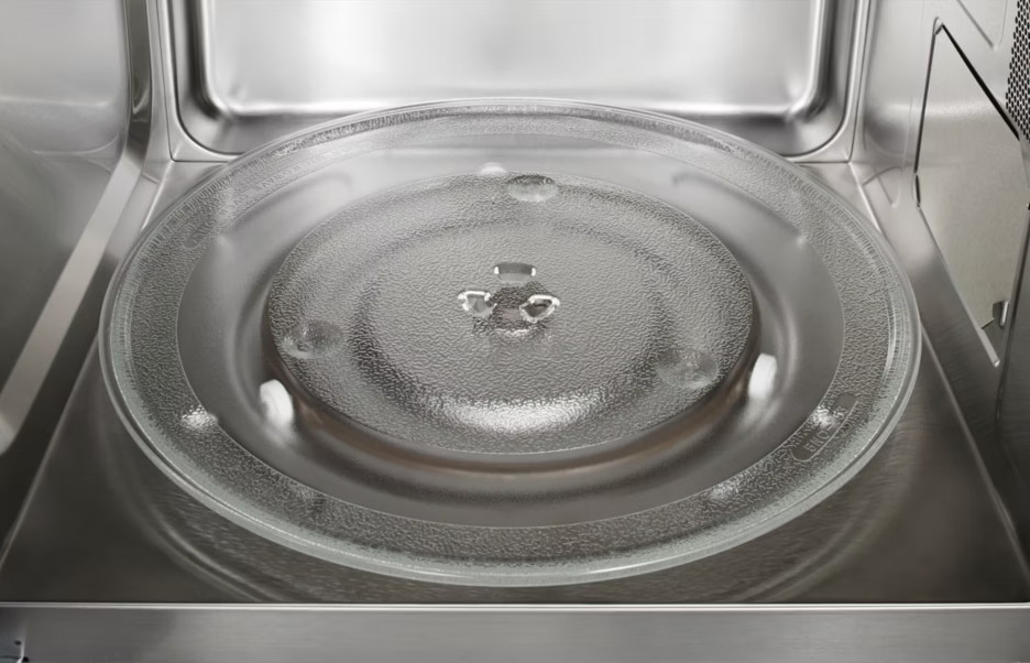 Wnętrze kuchenki mikrofalowej. Przezroczysty szklany talerz leży na metalowej podstawie. Wnętrze jest ze stali nierdzewnej.