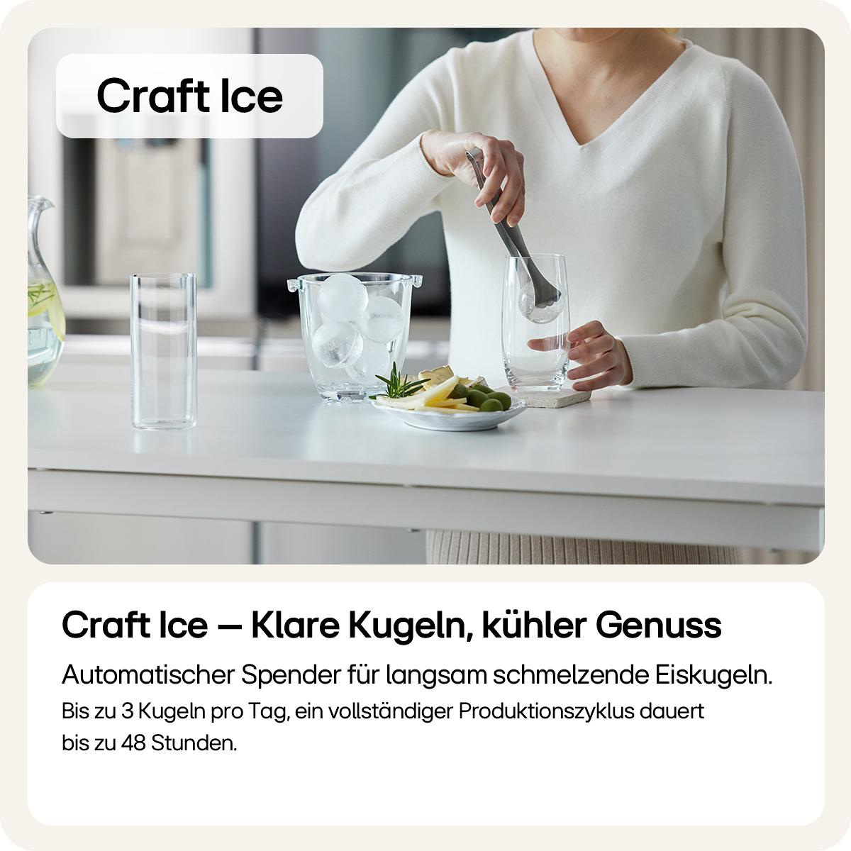 Eine Person legt mit einer Eiszange eine Eiskugel in ein Glas. Ein Teller mit Oliven und Käse ist im Vordergrund.